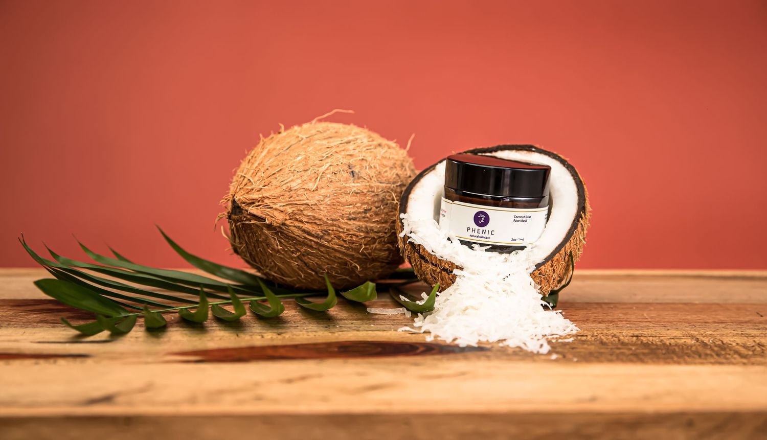 Tropical-themed product photography with coconut and palm leaves against coral background.