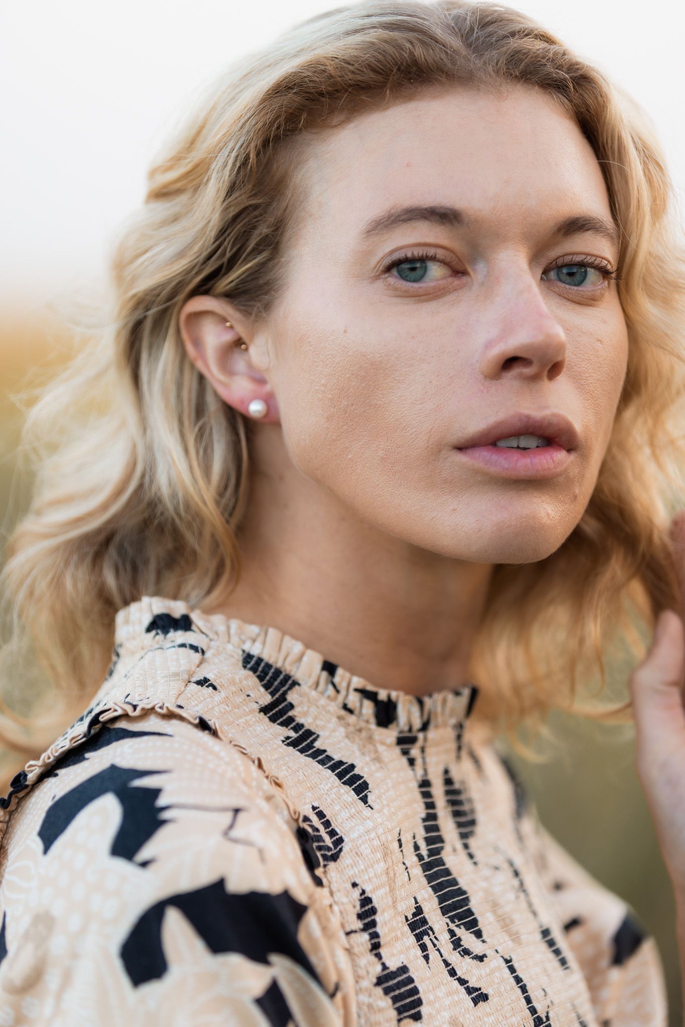 Close-up fashion shots featuring a cream-colored top with black graphic print pattern.