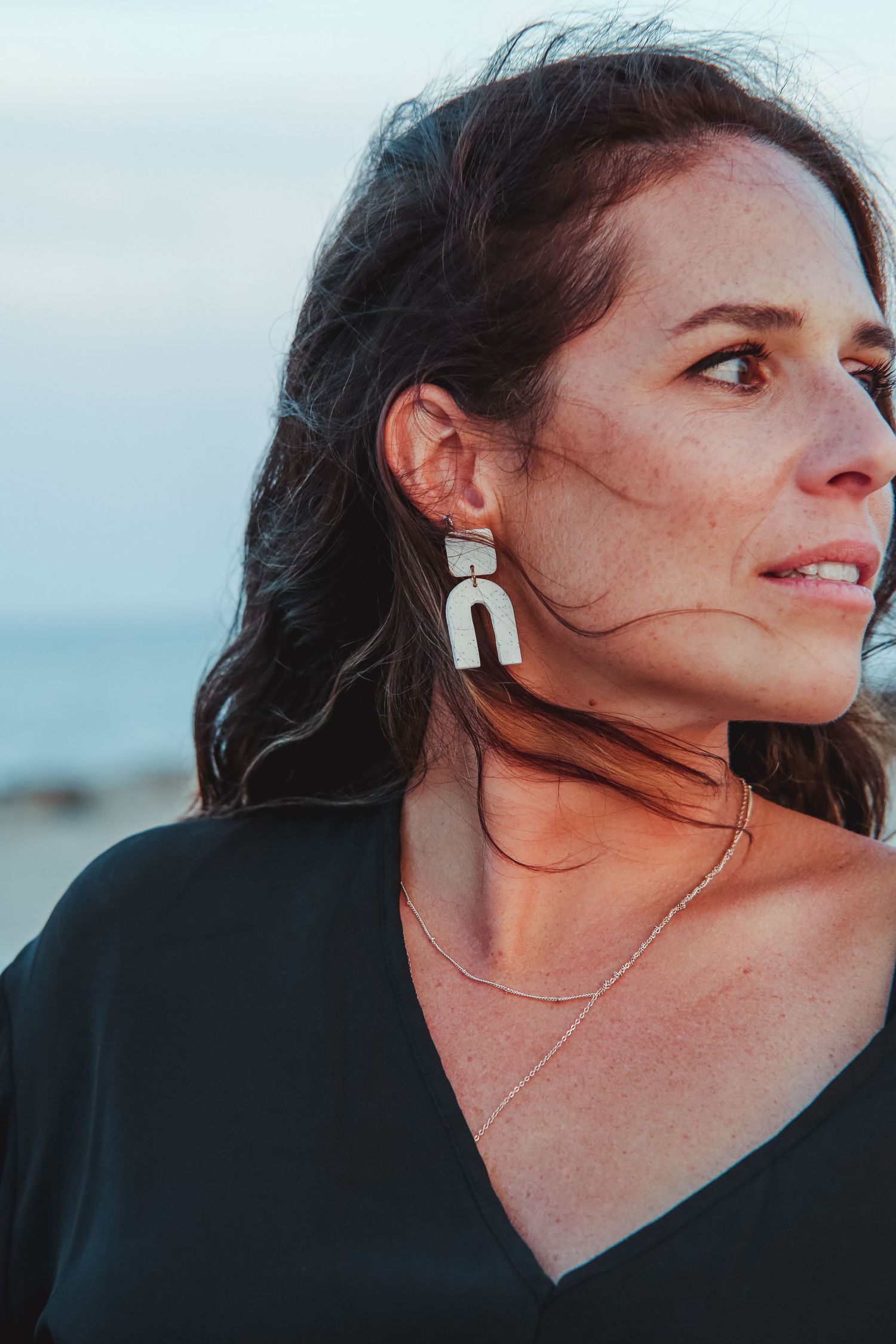 Artistic profile shot showcasing modern white geometric statement earrings at sunset.