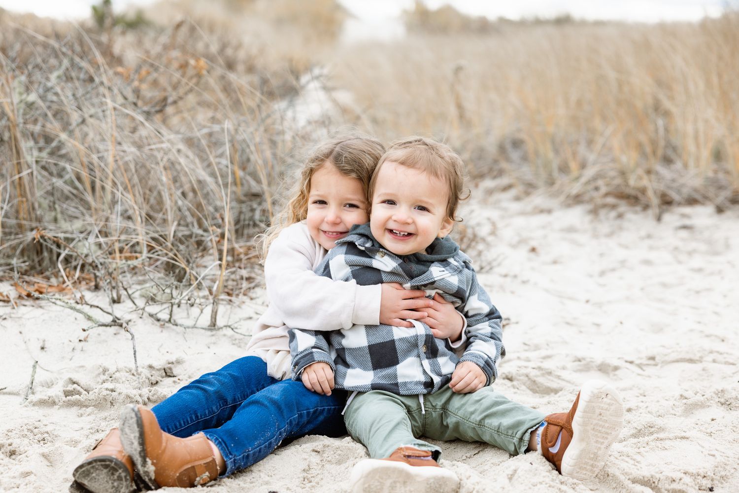 Children playing and laughing together on a sandy beach path.