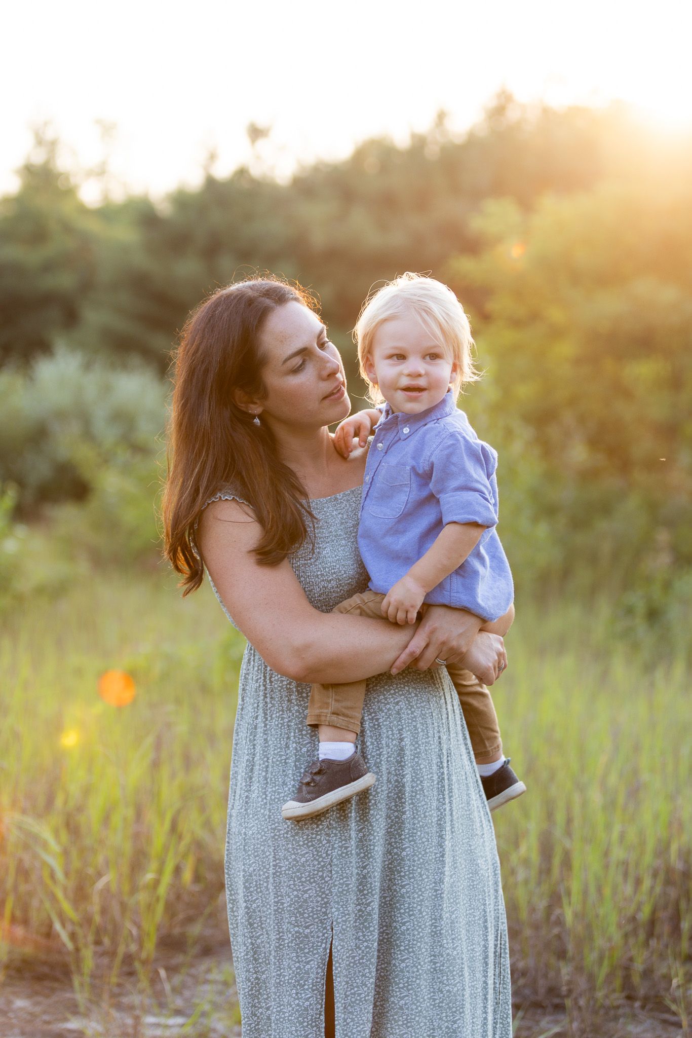 Tender family moments captured in a field during sunset with a parent and child.