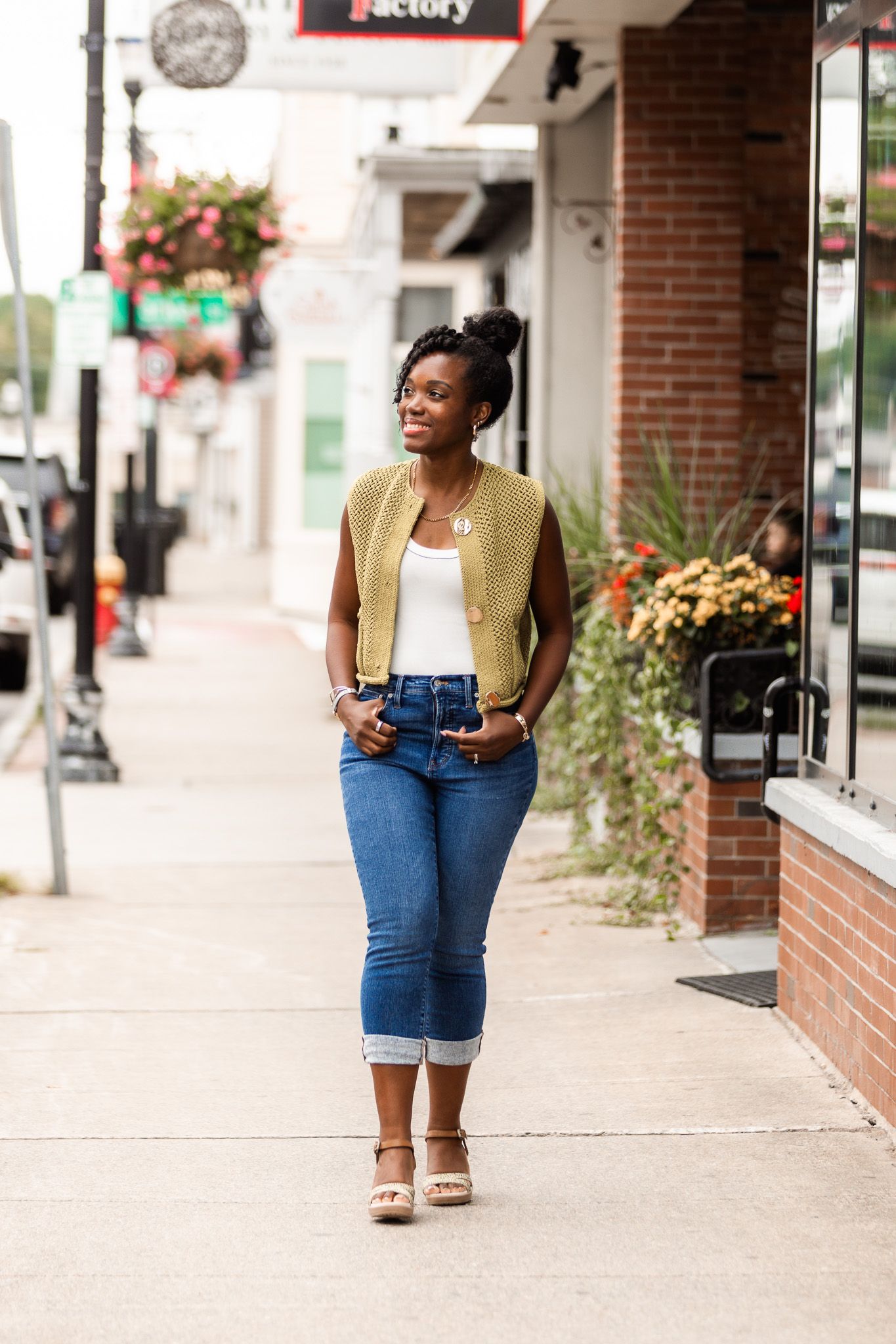 Street style photos of someone wearing denim shorts and a yellow vest against brick buildings.