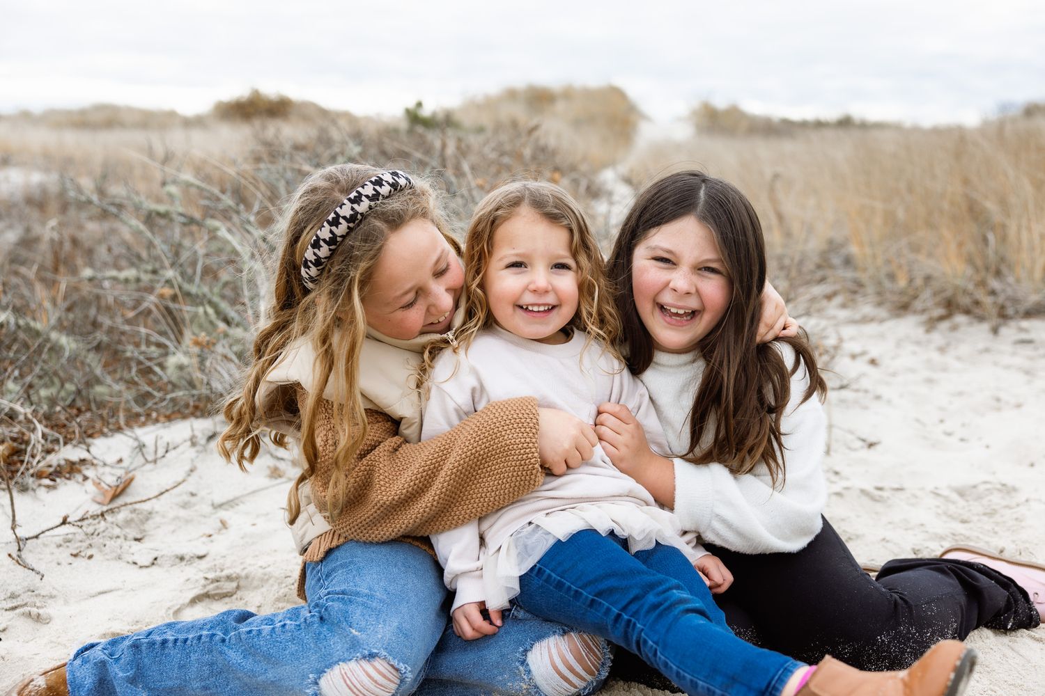 Kids cuddling and laughing together during outdoor family photo session.