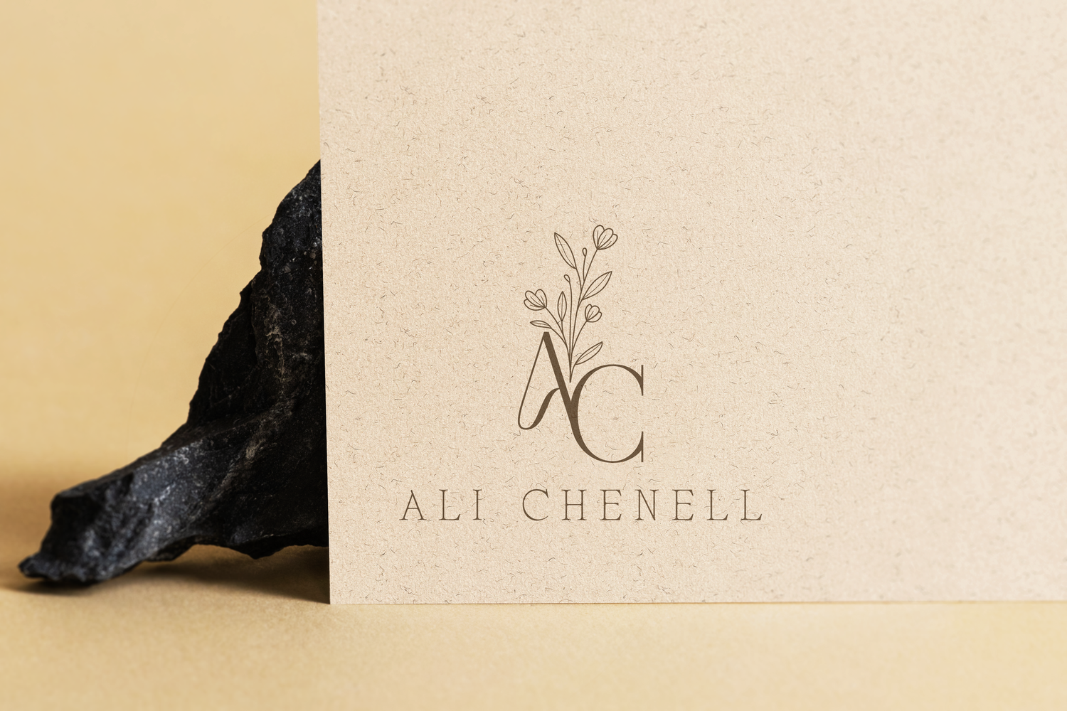 Elegant logo design for Ali Chenell featuring minimalist floral elements and text on cream colored paper.