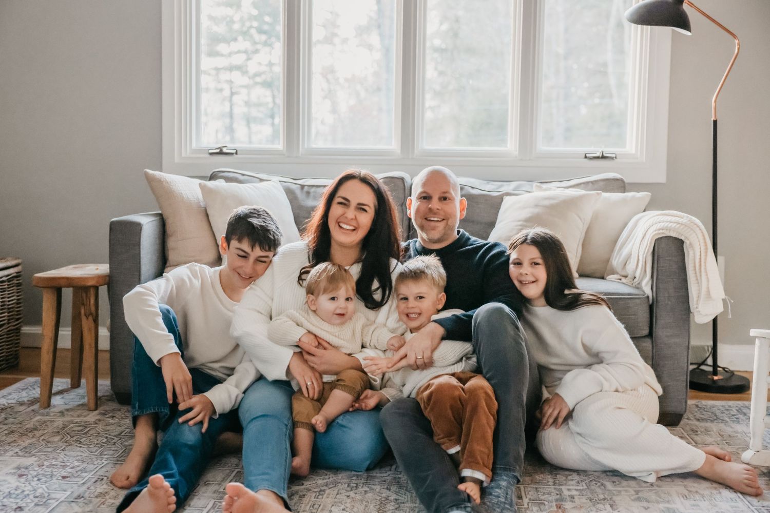 A cozy family scene in a bright living room with large windows and modern furniture.