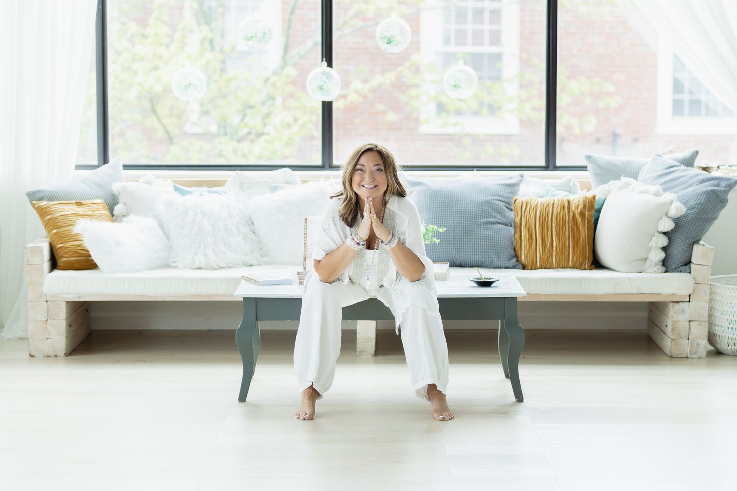Lifestyle photos on white couch in bright modern room with large windows.