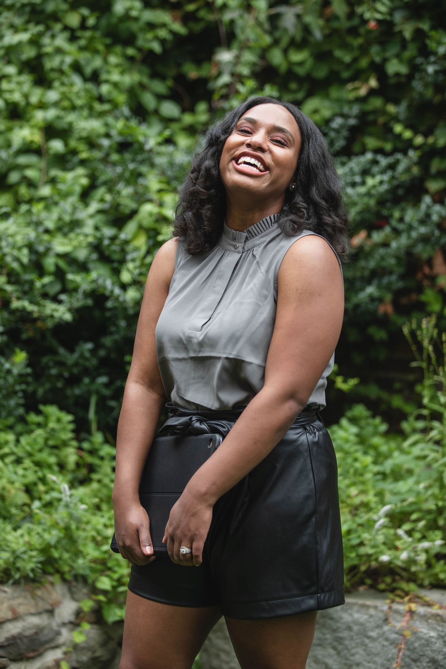 Outdoor portrait session with grey and black outfit against lush green foliage background.
