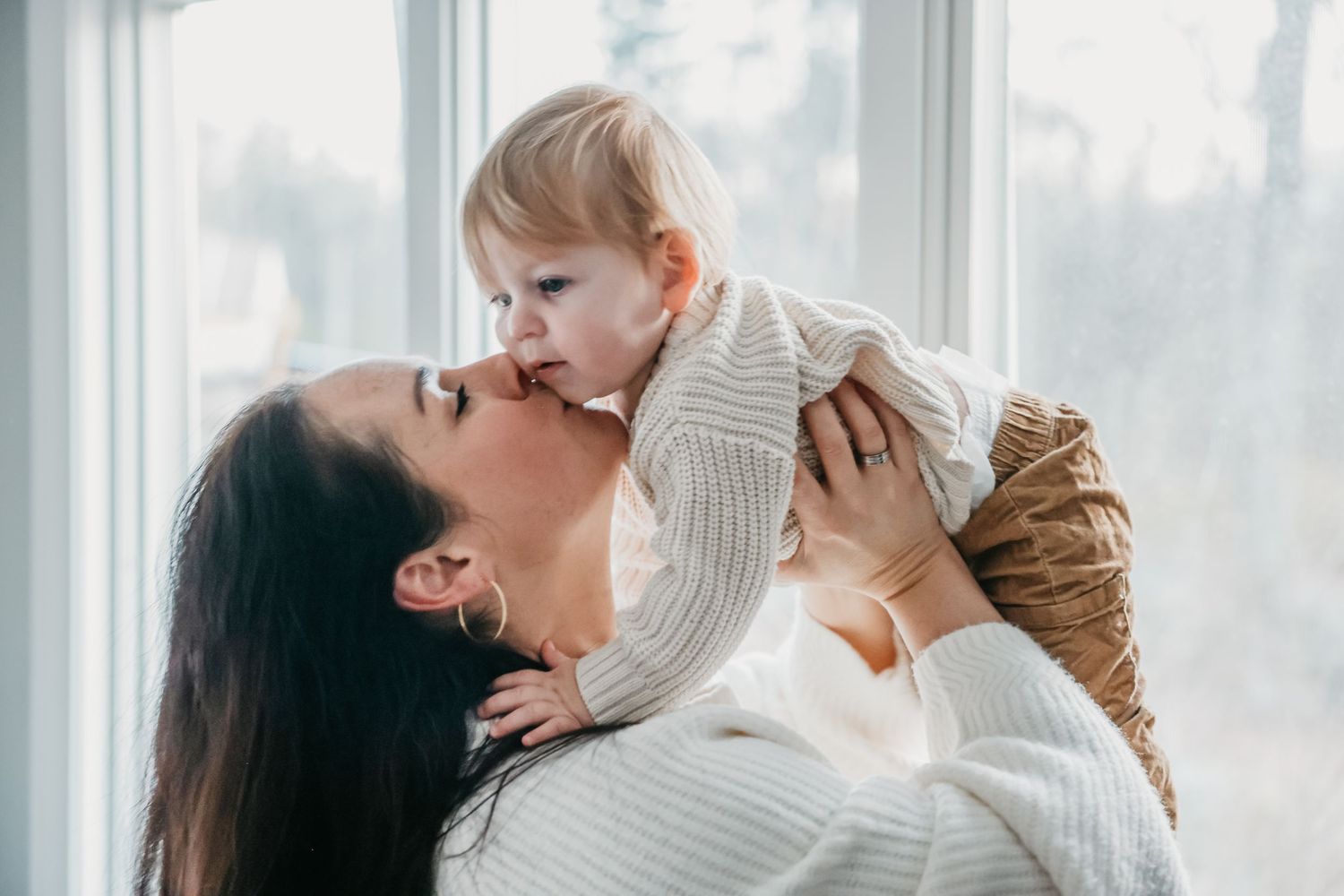 A tender family moment captured by a window with natural light streaming in.
