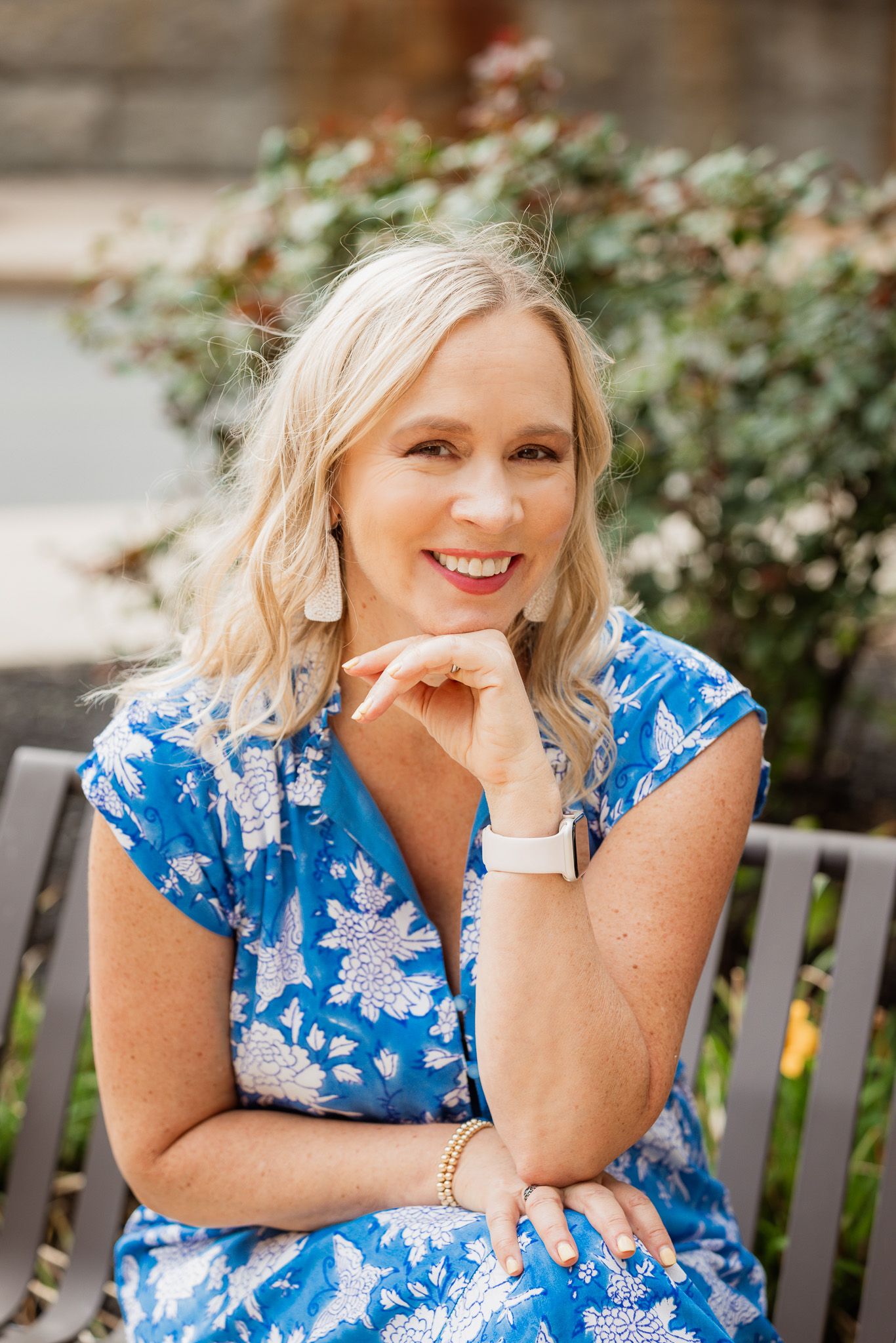 Casual outdoor portrait session on wooden bench with blue floral summer dress.