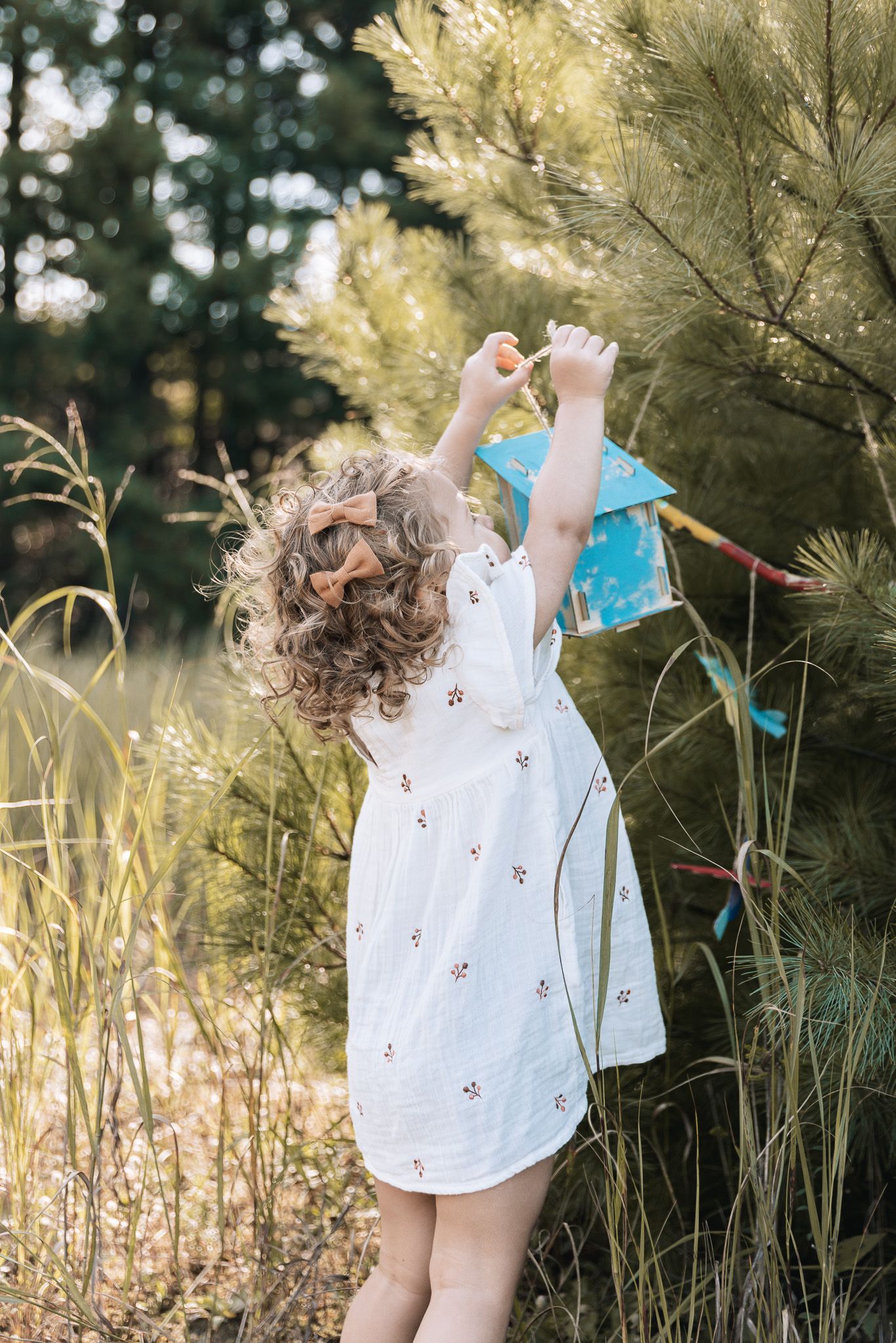 A child in white dress dances among tall grasses in soft natural lighting.