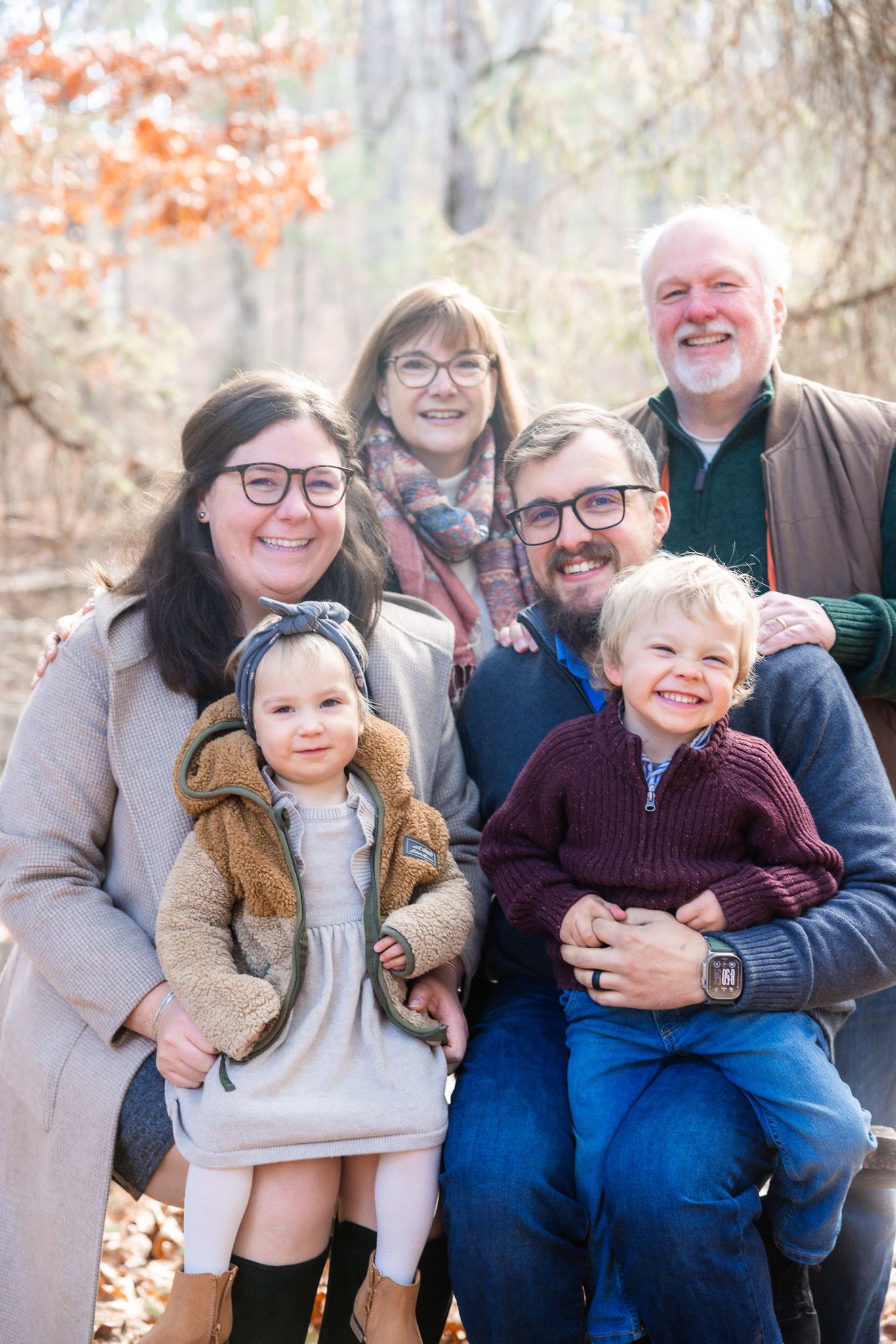Multi-generational family sitting together outdoors during an autumn photo session.