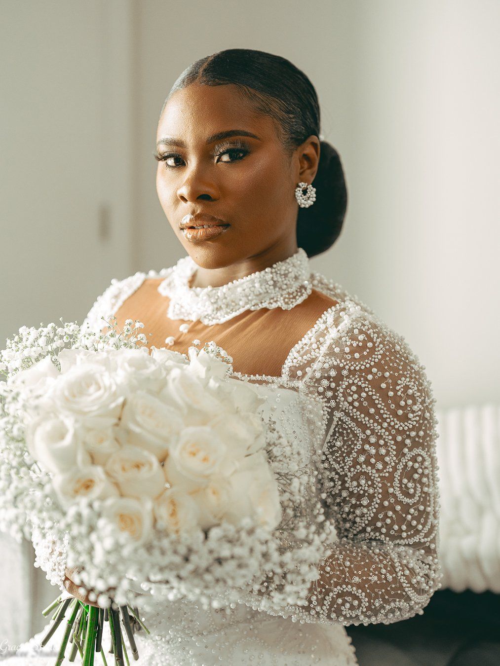 Elegant portrait of a bride in a beaded pearl wedding gown and white calla lily bouquet in natural light.