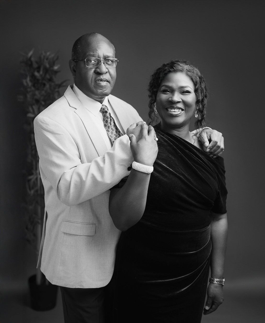 A couple in formal attire, one in white and one in black, share a joyful moment in black and white photography.