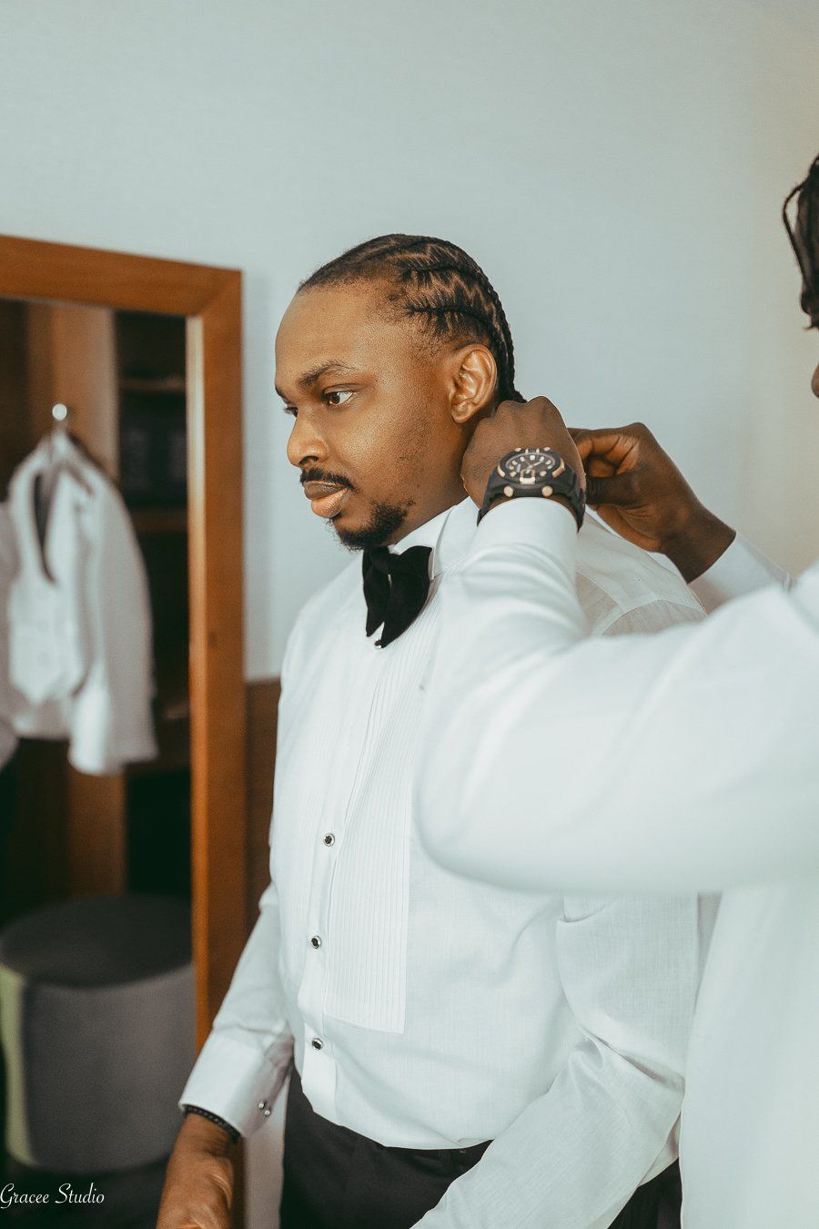 Groom in his crisp white tuxedo been fixed up.