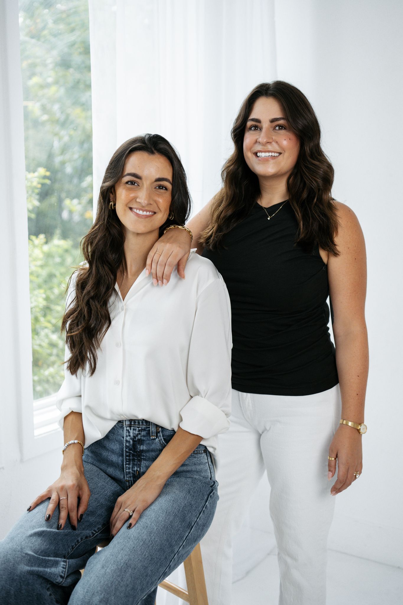 Two women in contrasting outfits sharing candid moments during a bright studio photography session.