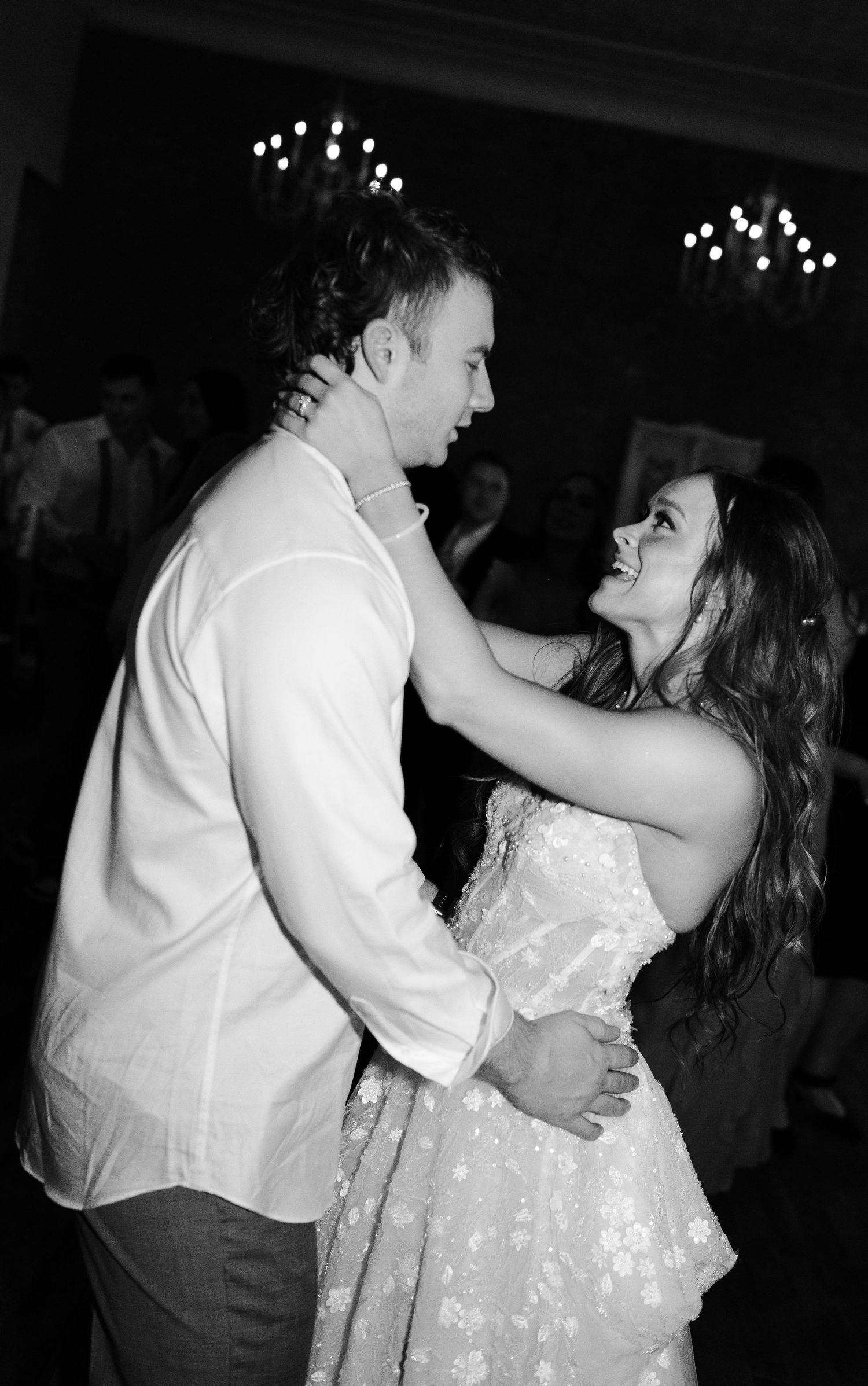 Black and white photo of a couple dancing and smiling at each other at a formal event.