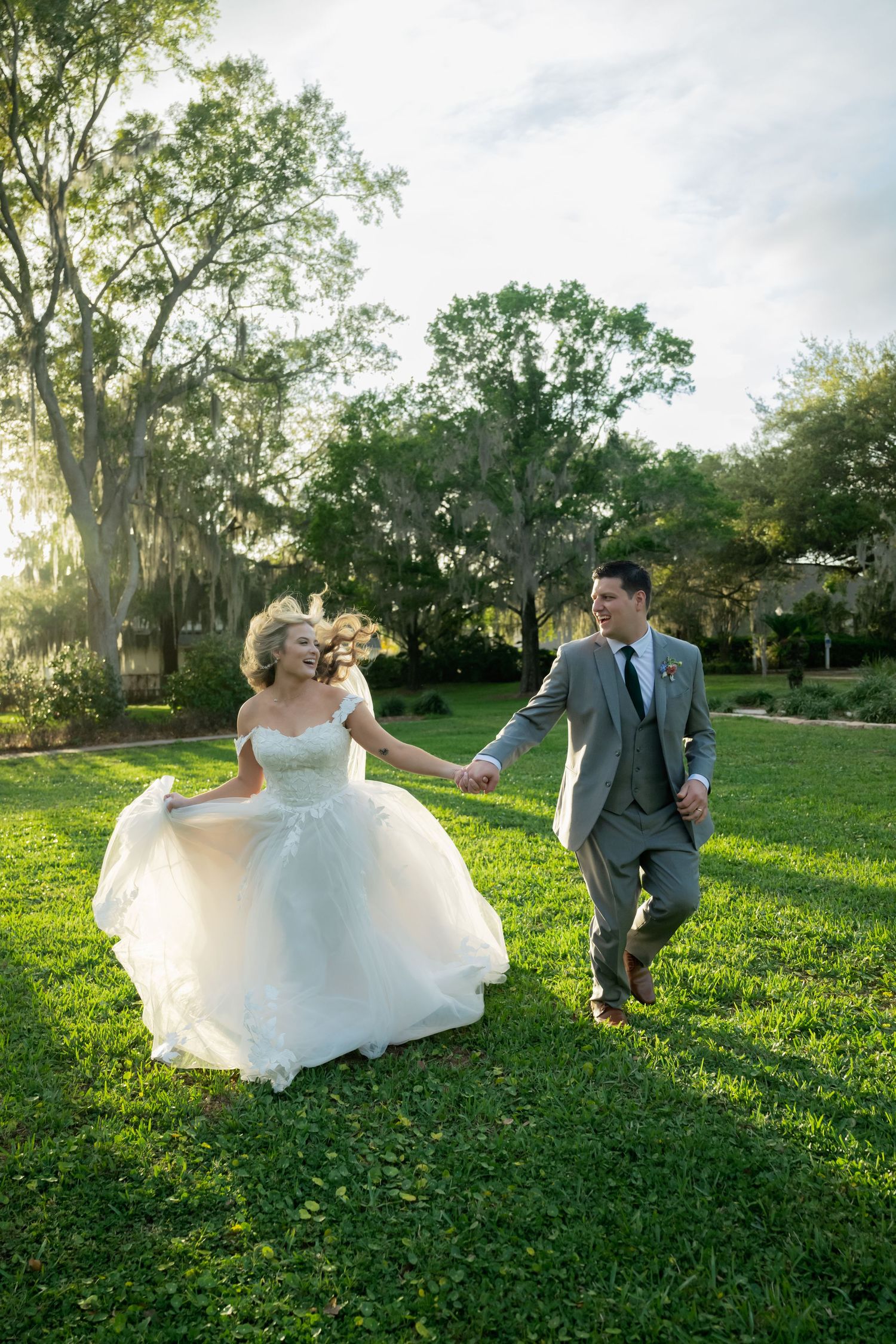 Couple playfully poses in sunlit garden setting during their wedding photoshoot.