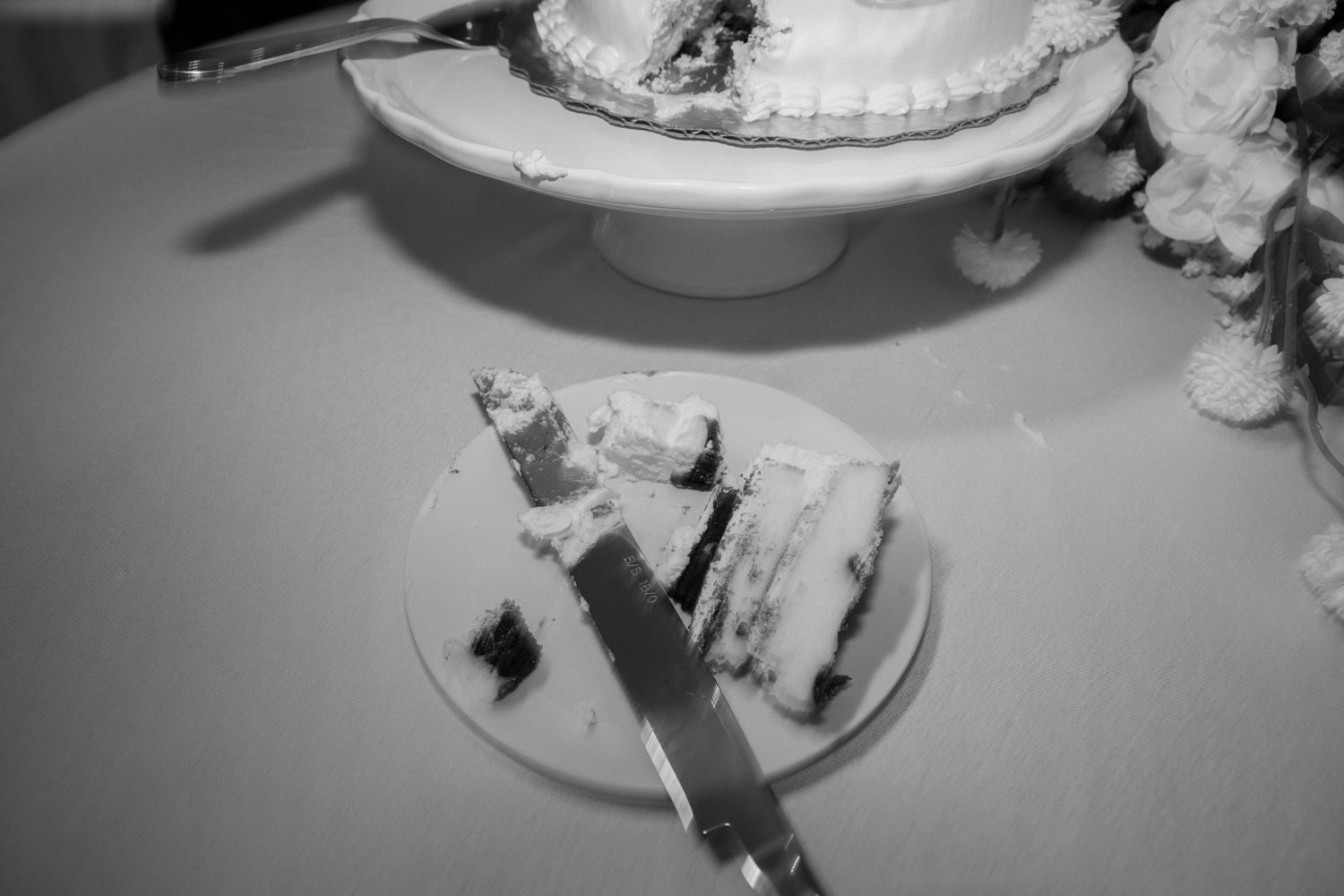 Wedding reception table setting with elegant cake and place settings in black and white photography.