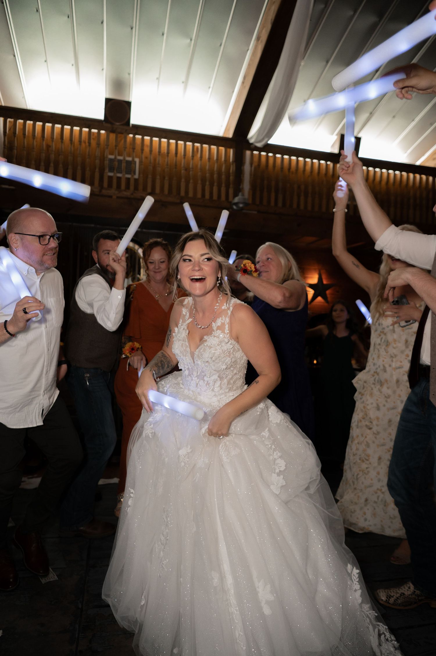 Wedding party dancing and celebrating under indoor lighting at reception venue.