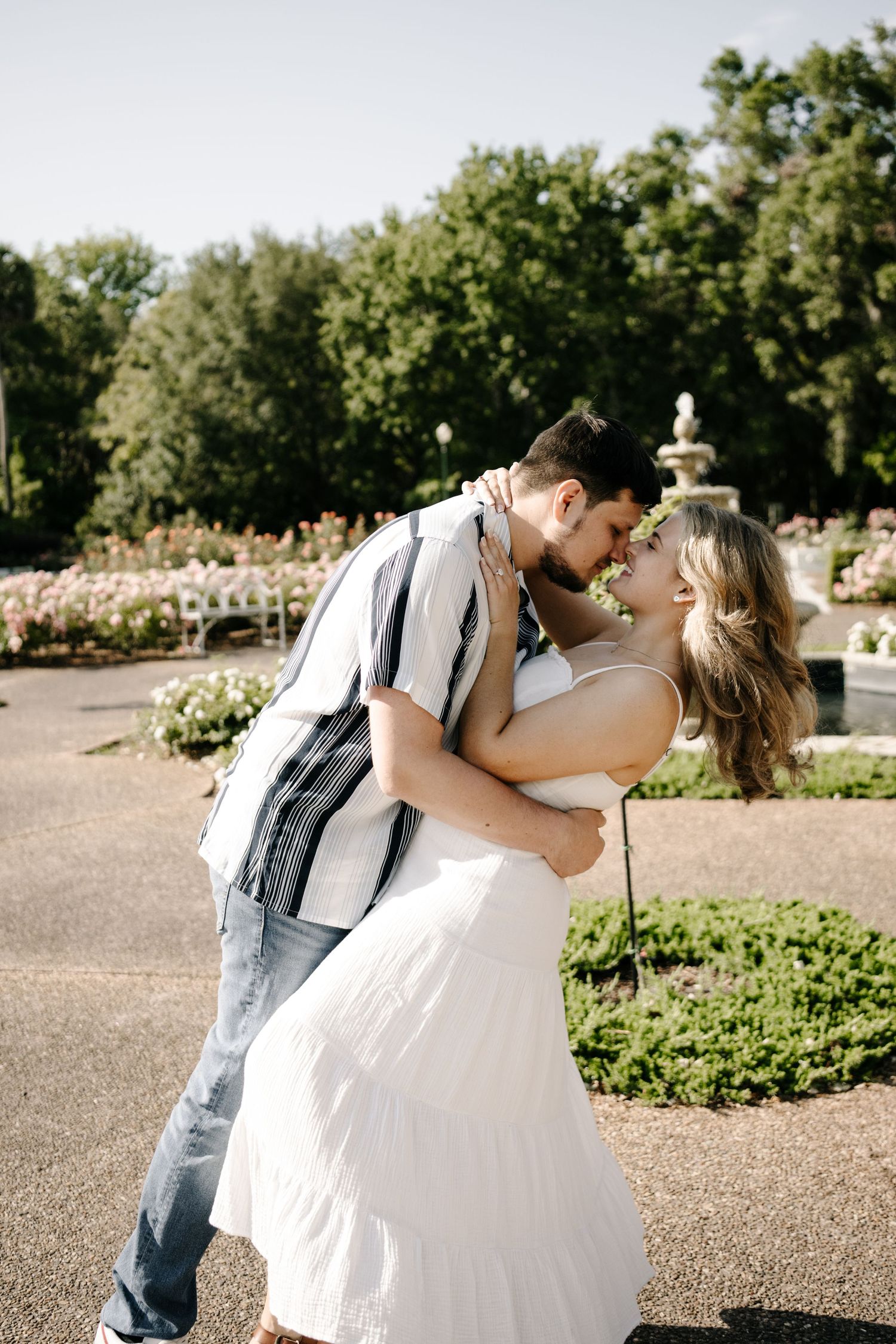 A romantic dip pose in a garden with blooming roses in the background.