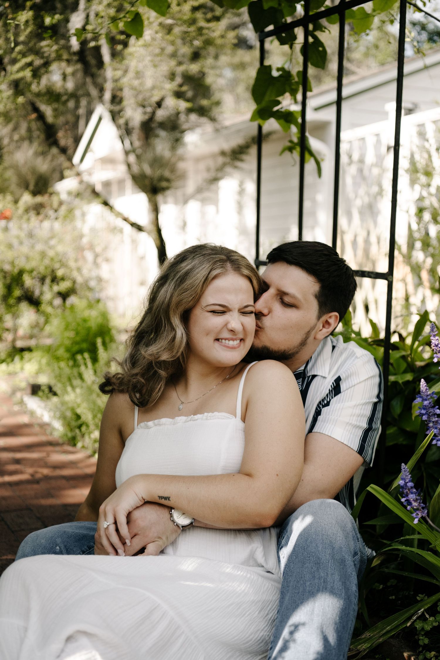 A tender moment shared between a couple sitting in a lush garden setting.