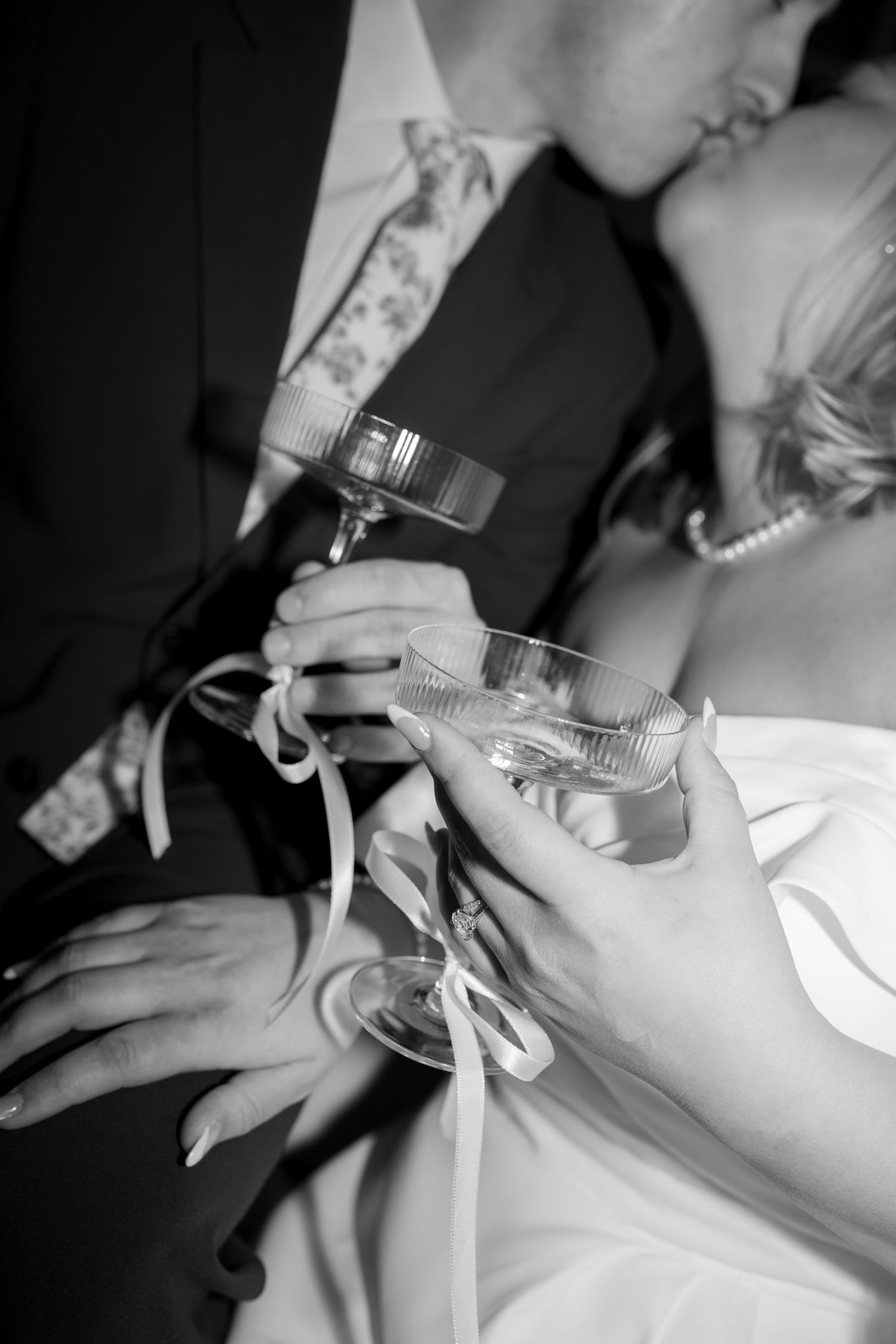Wedding details including lace veil, shoes, and champagne bottle on wooden floor.