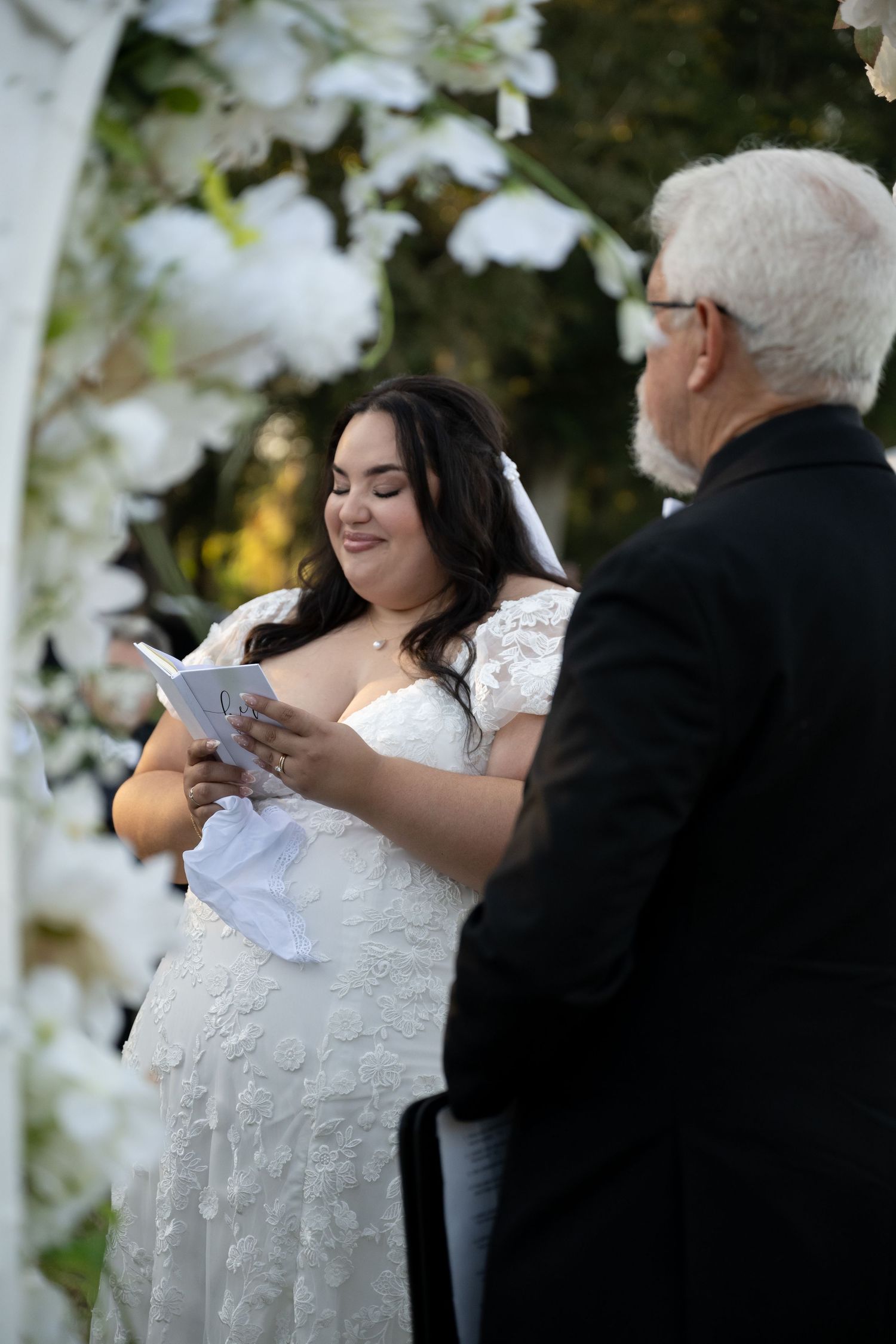 Wedding ceremony participants reading from papers during an outdoor service.