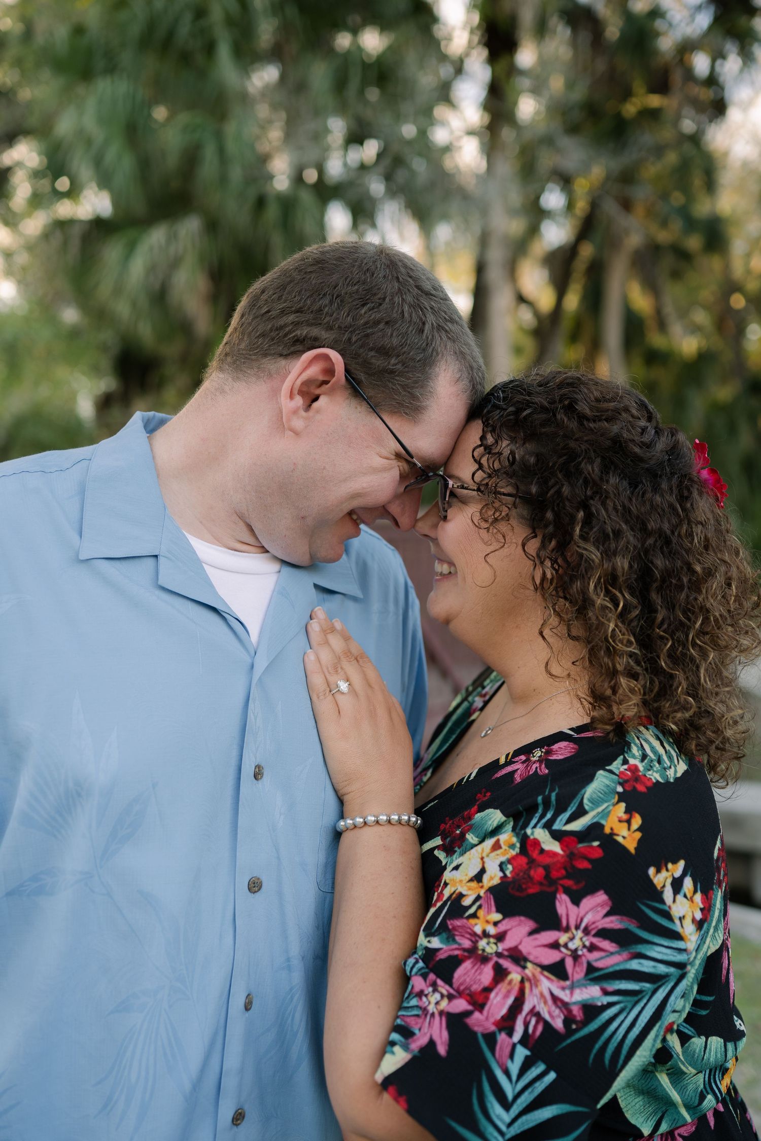A couple shares an intimate moment while smiling at each other in a garden setting.