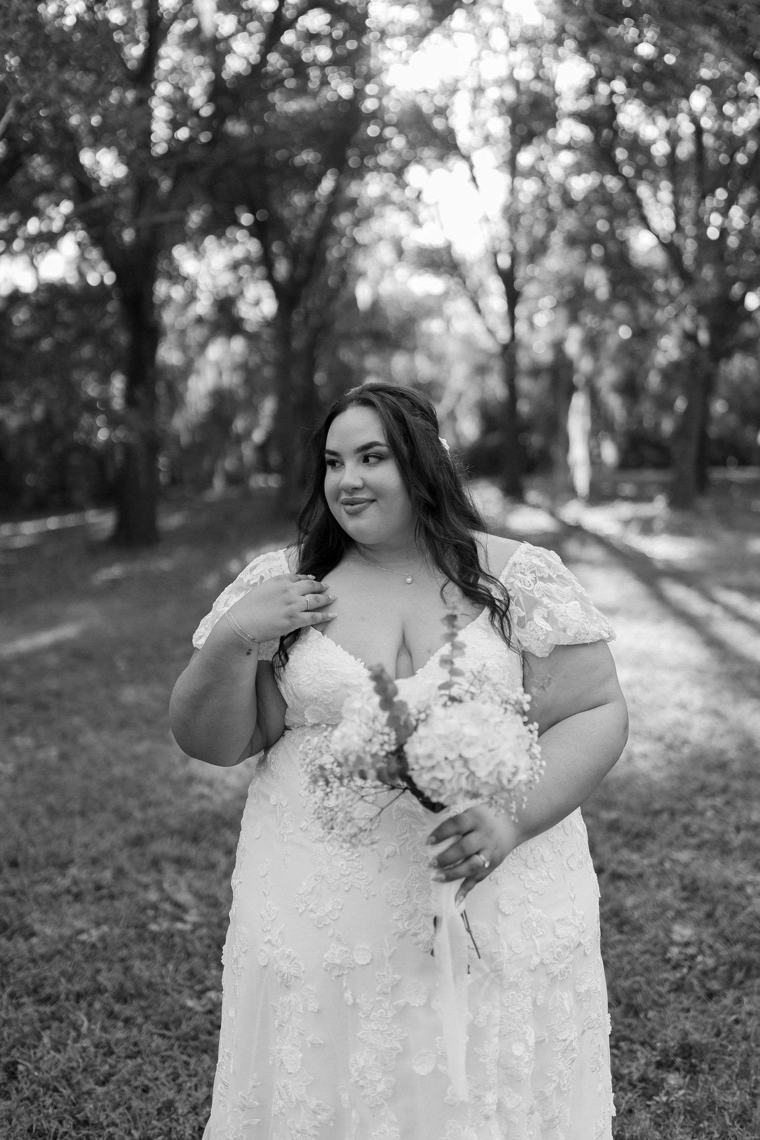 A lace wedding dress is photographed in a sunlit outdoor setting.