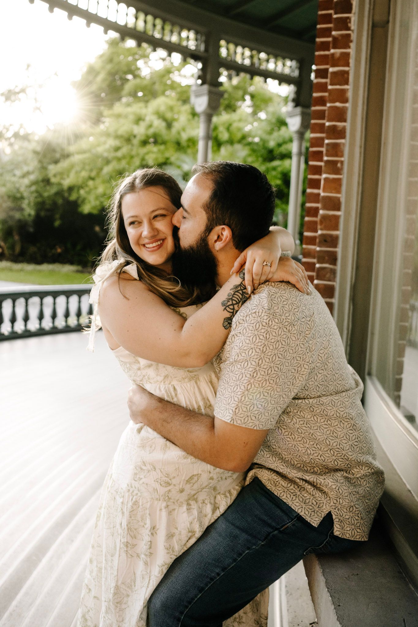 A loving couple shares an intimate moment on a sunlit veranda.