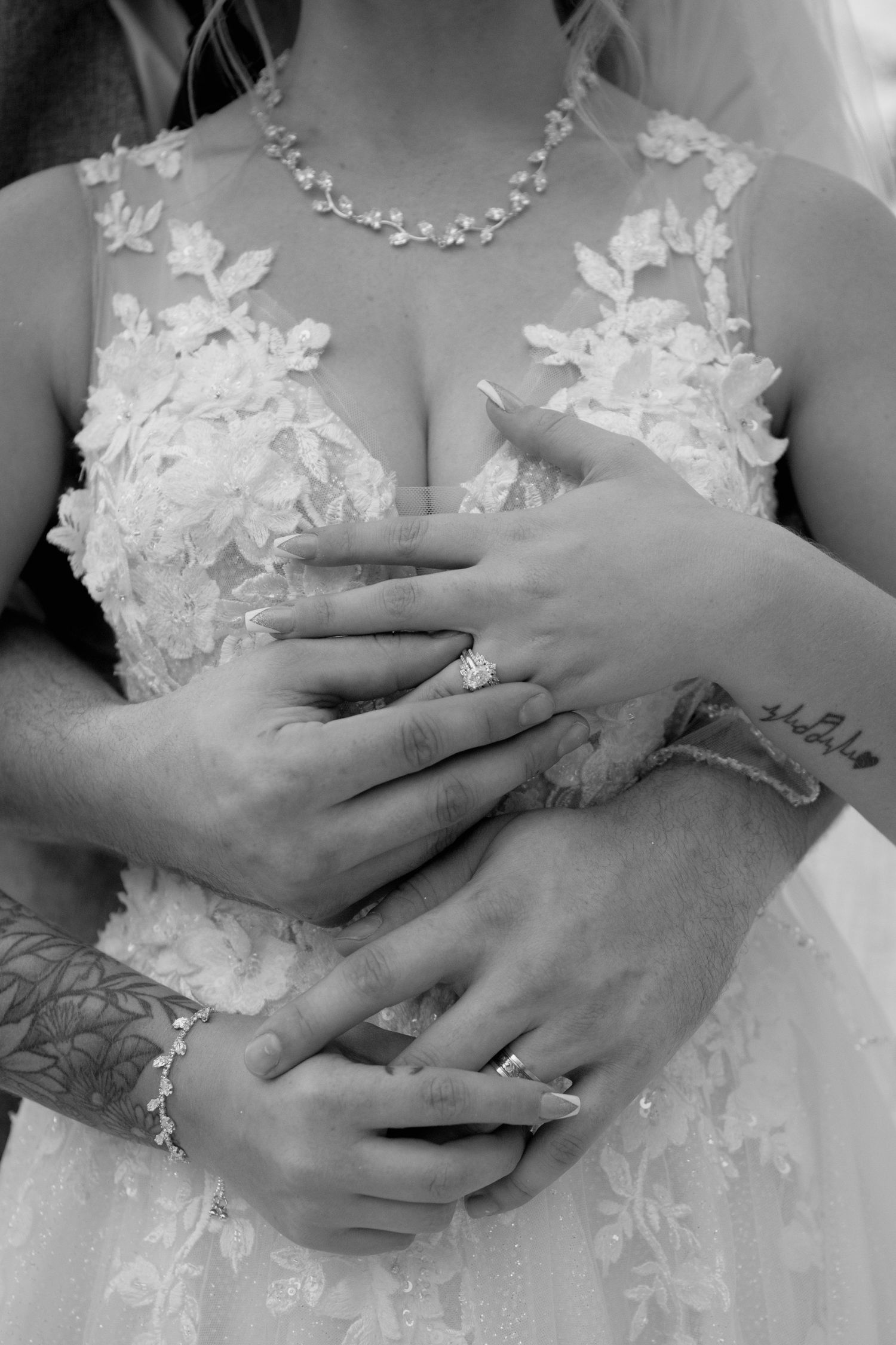 Black and white close-up shots of hands with wedding rings against lace wedding dress details.