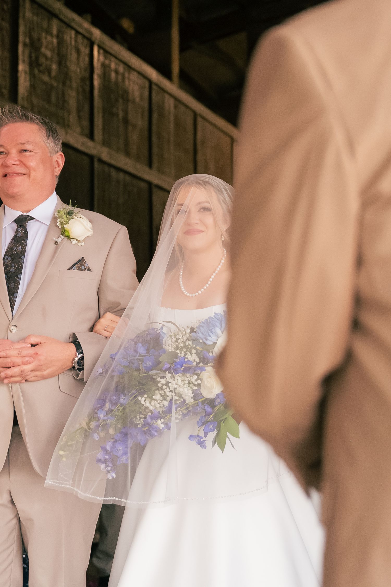 Wedding party in beige suits and white dress poses together during outdoor ceremony.