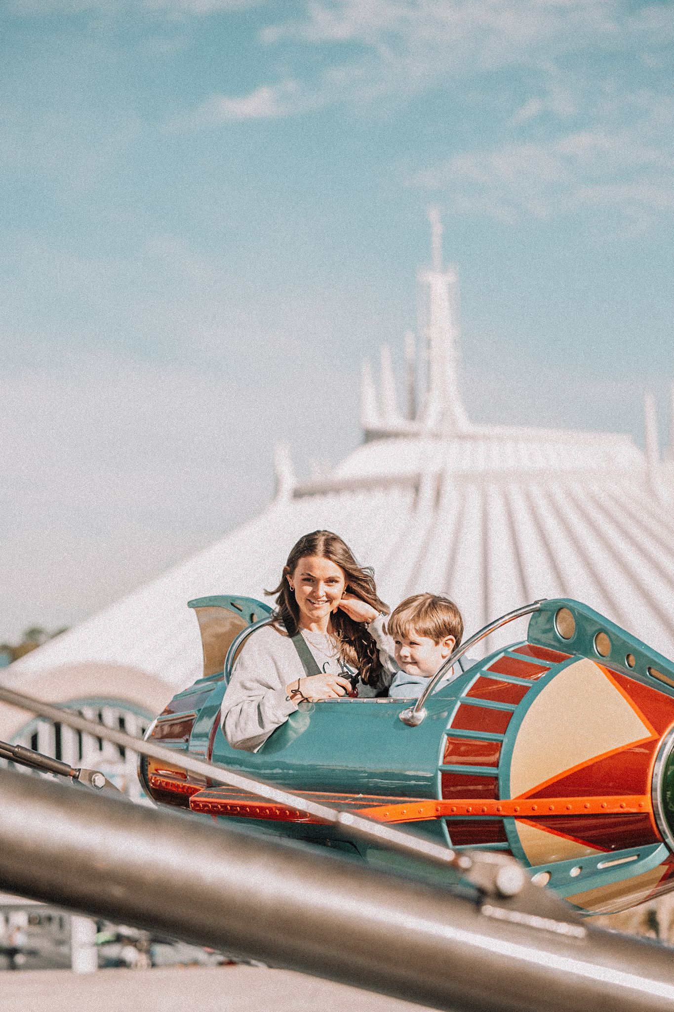Guests enjoying ride on retro-styled rocket ships at Space Mountain attraction.