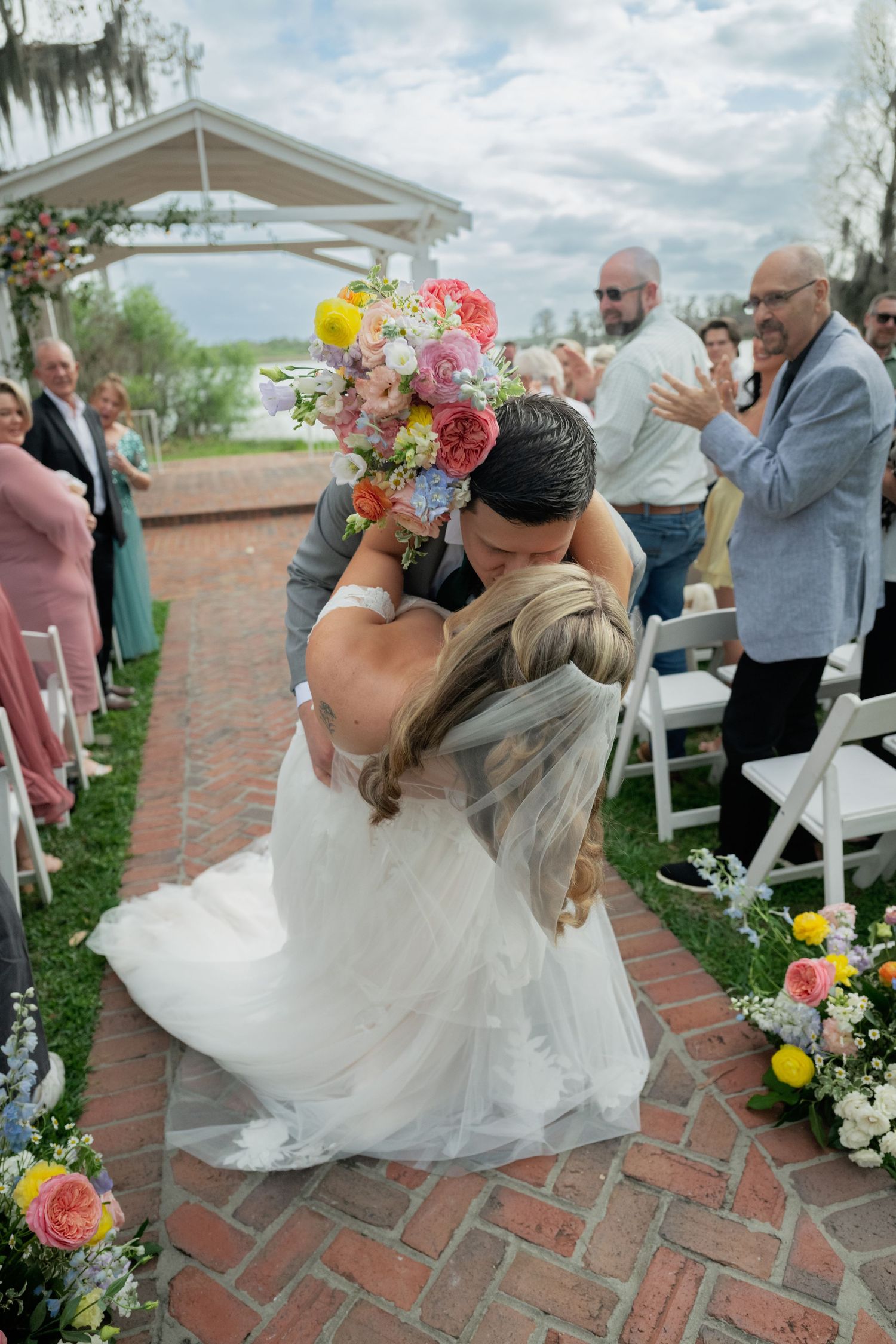 Wedding celebration sequence showing joyful dance moves on brick pathway outdoors.