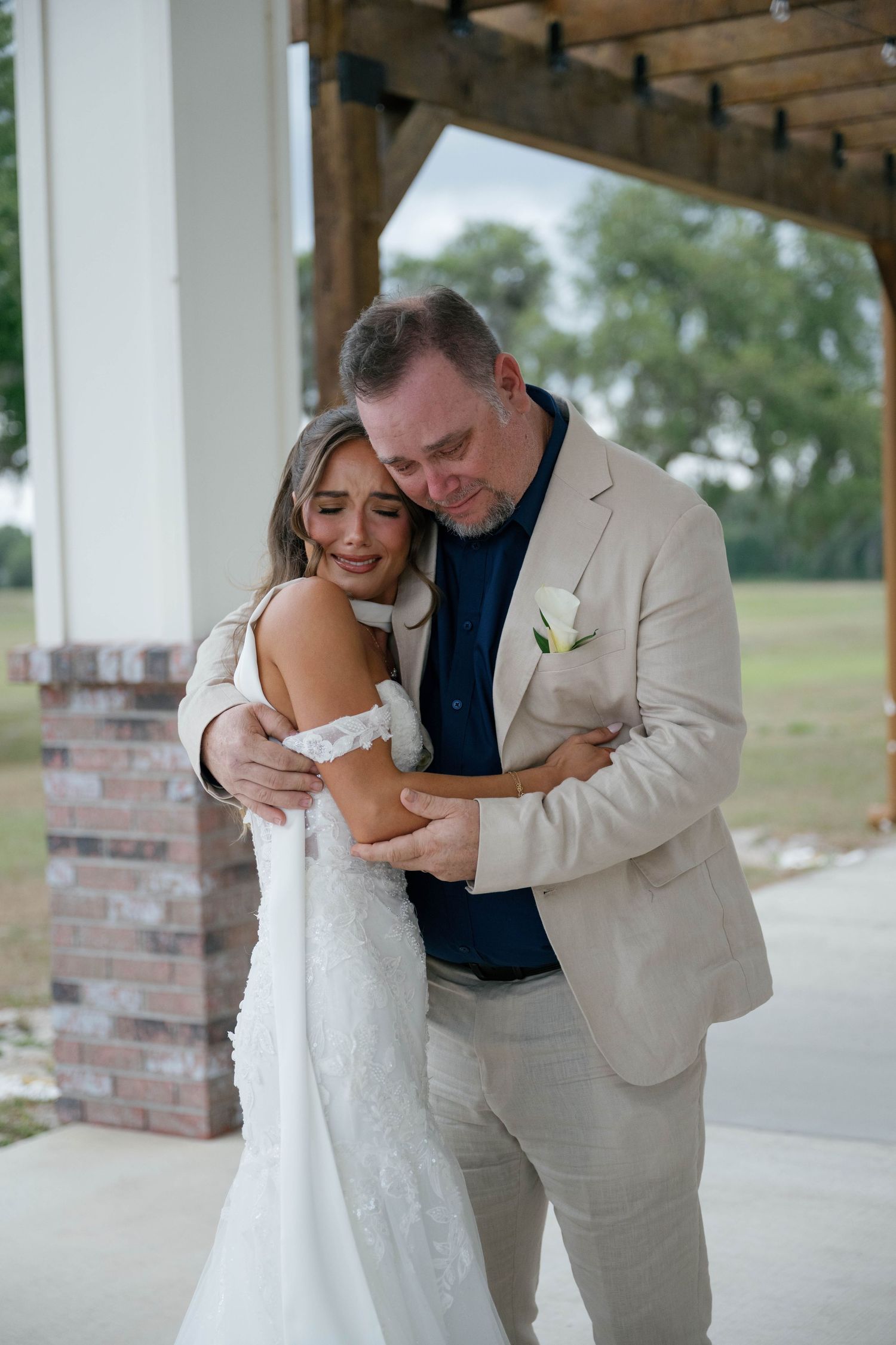 Emotional bride and groom sharing a tender embrace on their wedding day, with the bride in a lace gown.