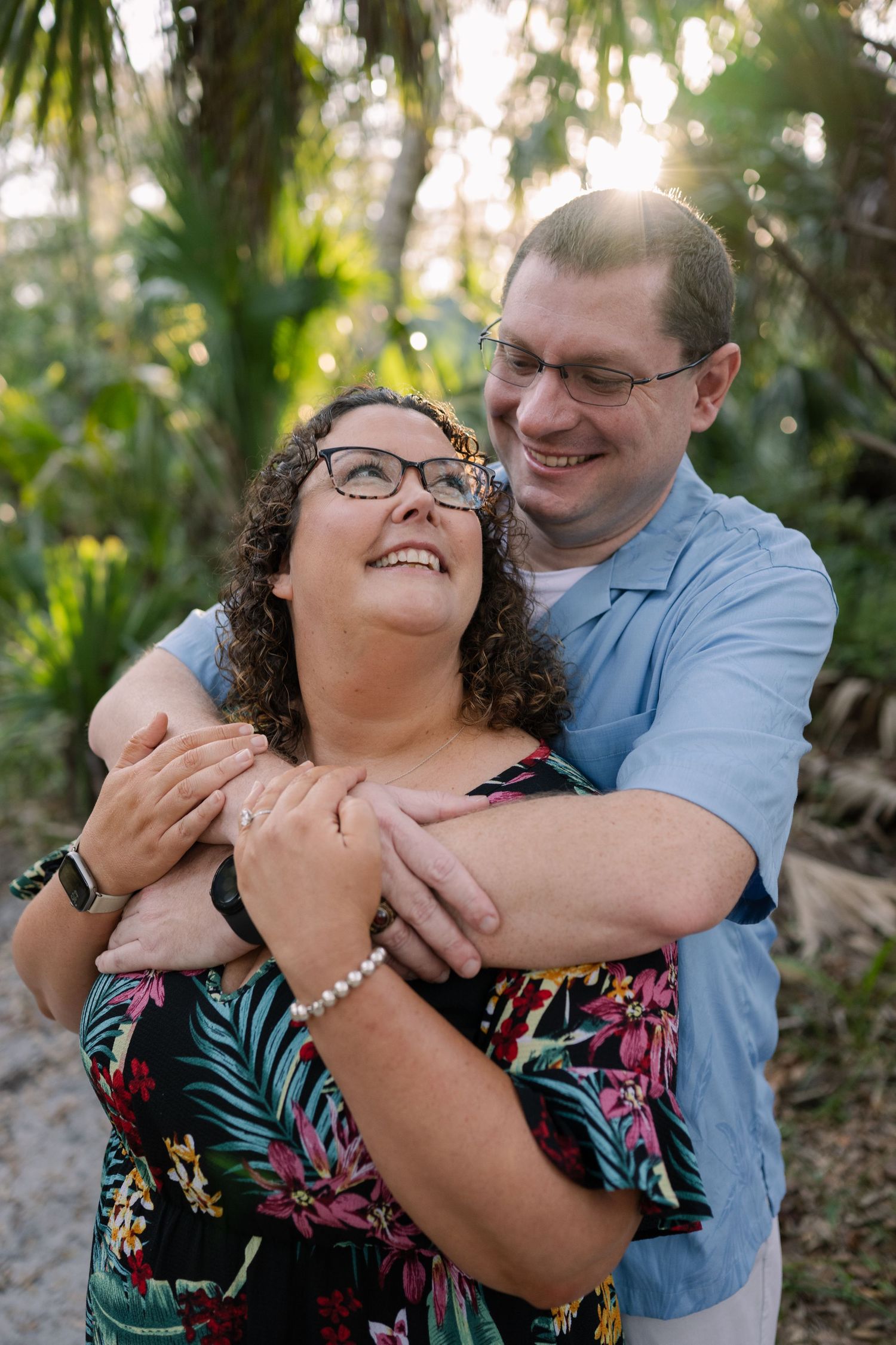 A couple shares a tender embrace in a tropical garden setting.