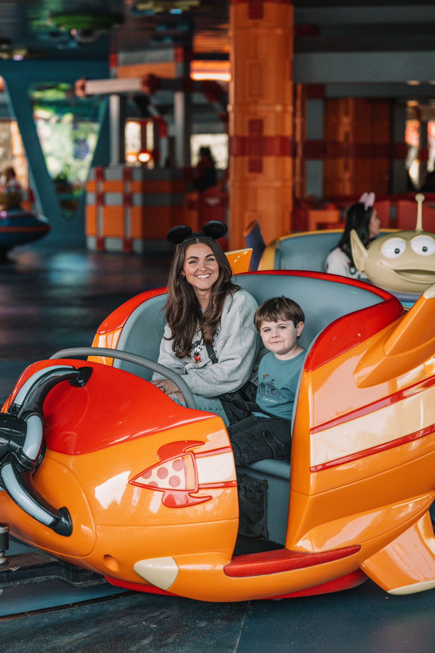 Orange rocket-shaped ride vehicles at indoor Disney attraction.