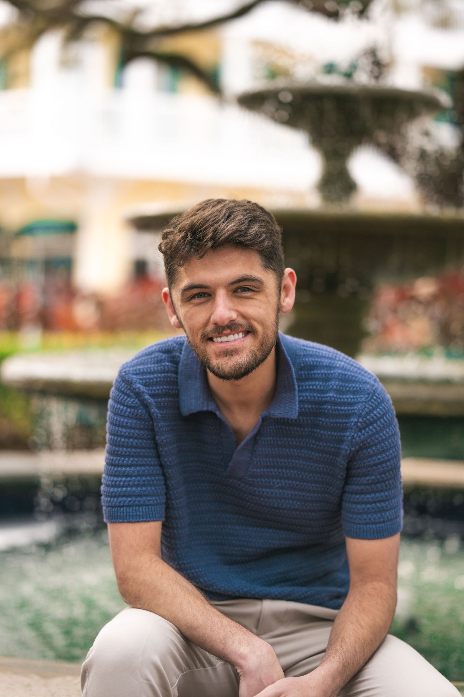 Portrait series of person in blue polo shirt sitting outdoors with natural lighting.