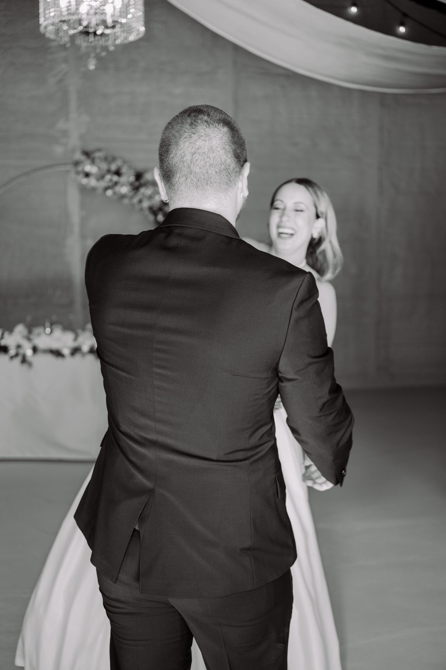 Black and white candid dance sequence of wedding couple in formal attire.