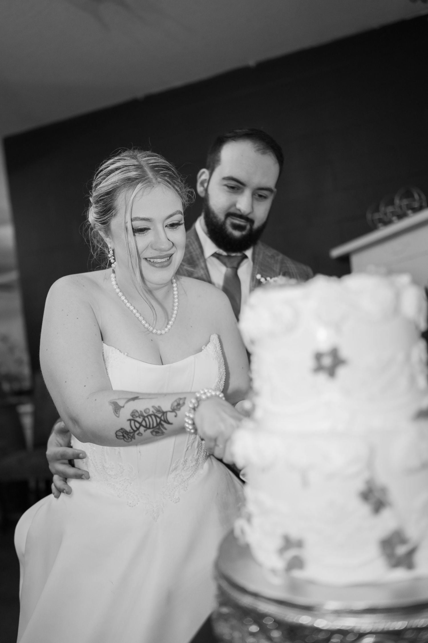 A sequence of black and white photos showing a couple cutting their wedding cake together at their reception.