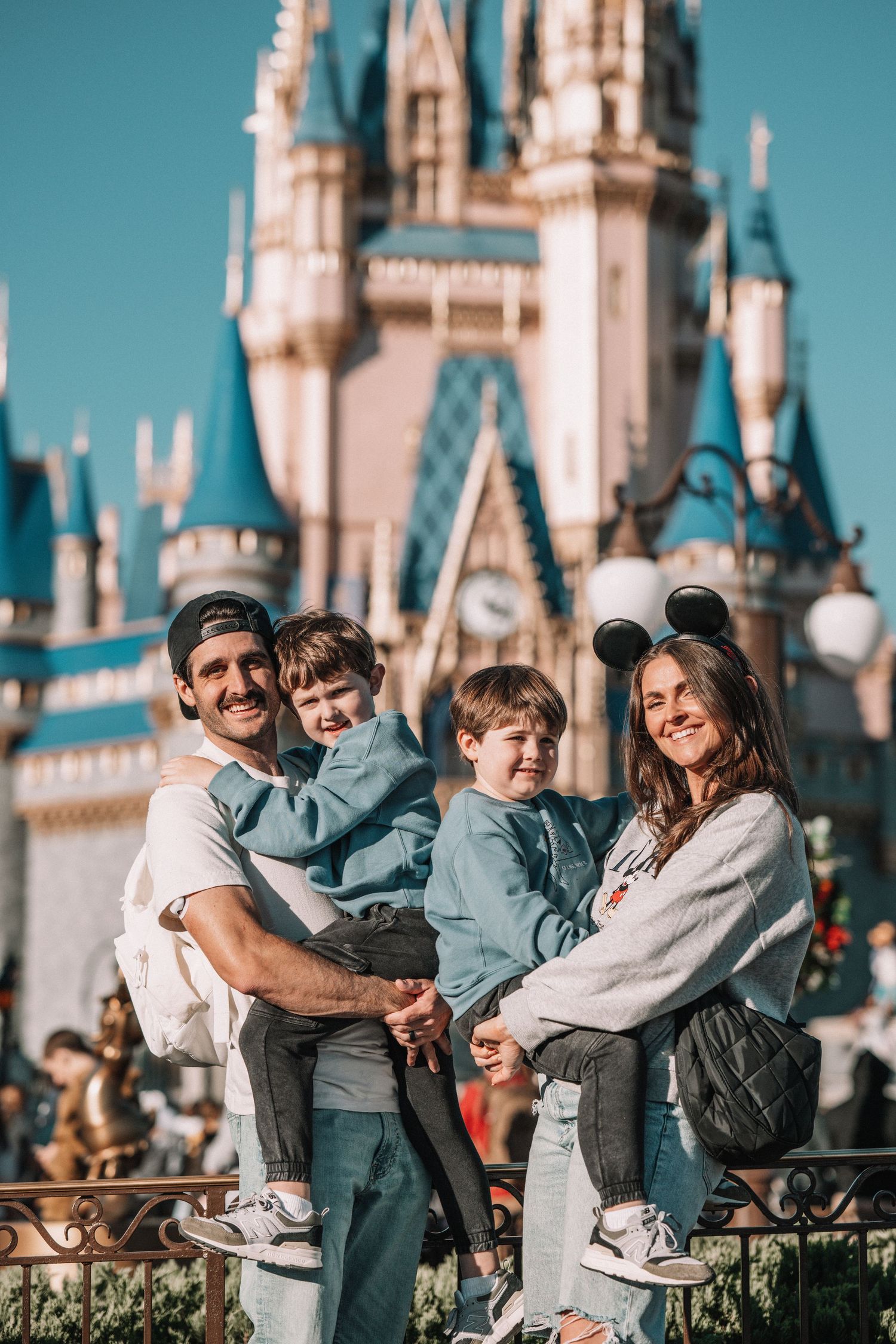 Family embracing in front of Cinderella Castle at Disney World on sunny day.