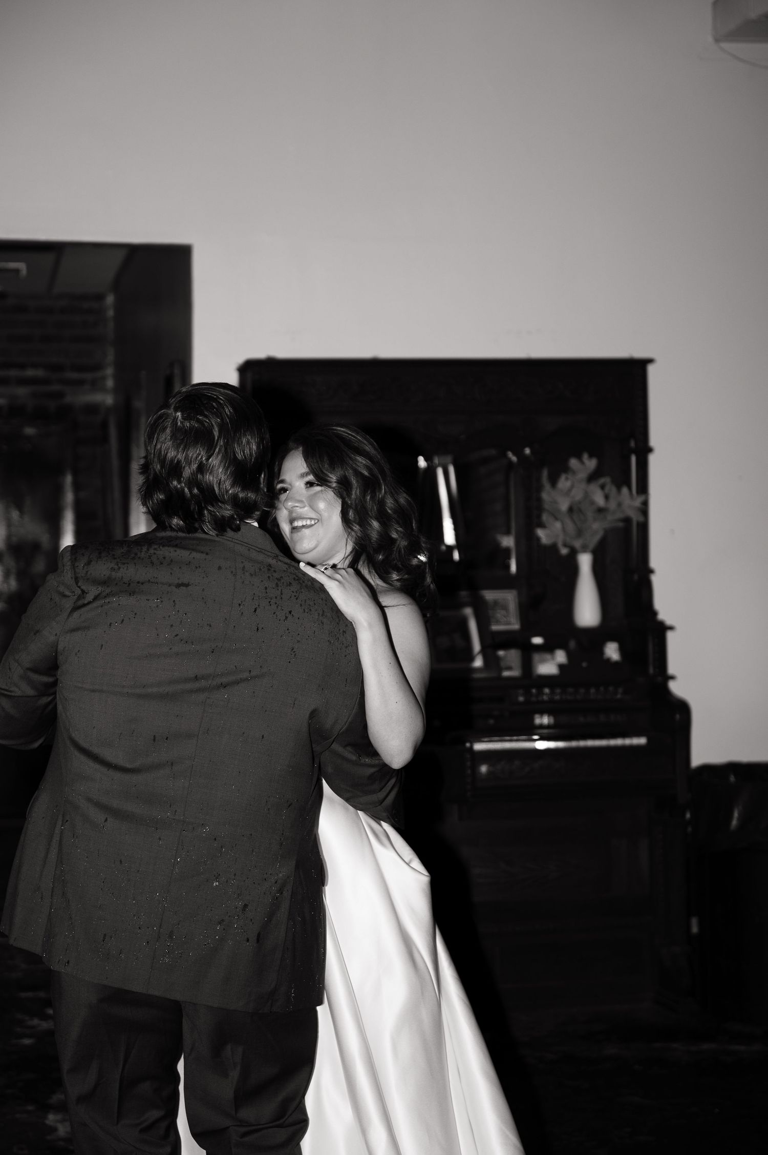 Bride and groom share intimate first dance in black and white wedding reception photo.