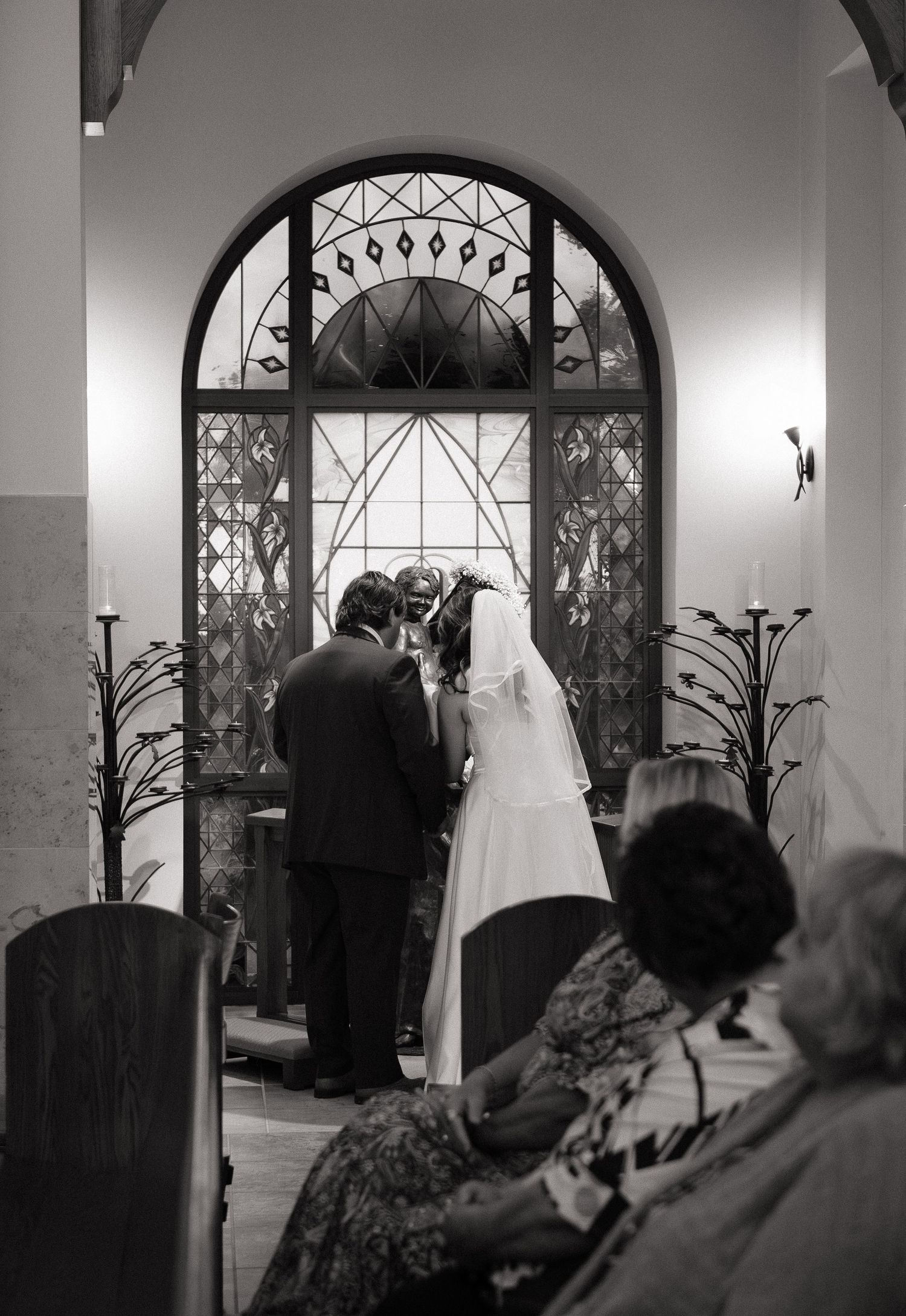 Bride and groom share a kiss at the altar during a church wedding ceremony in black and white.