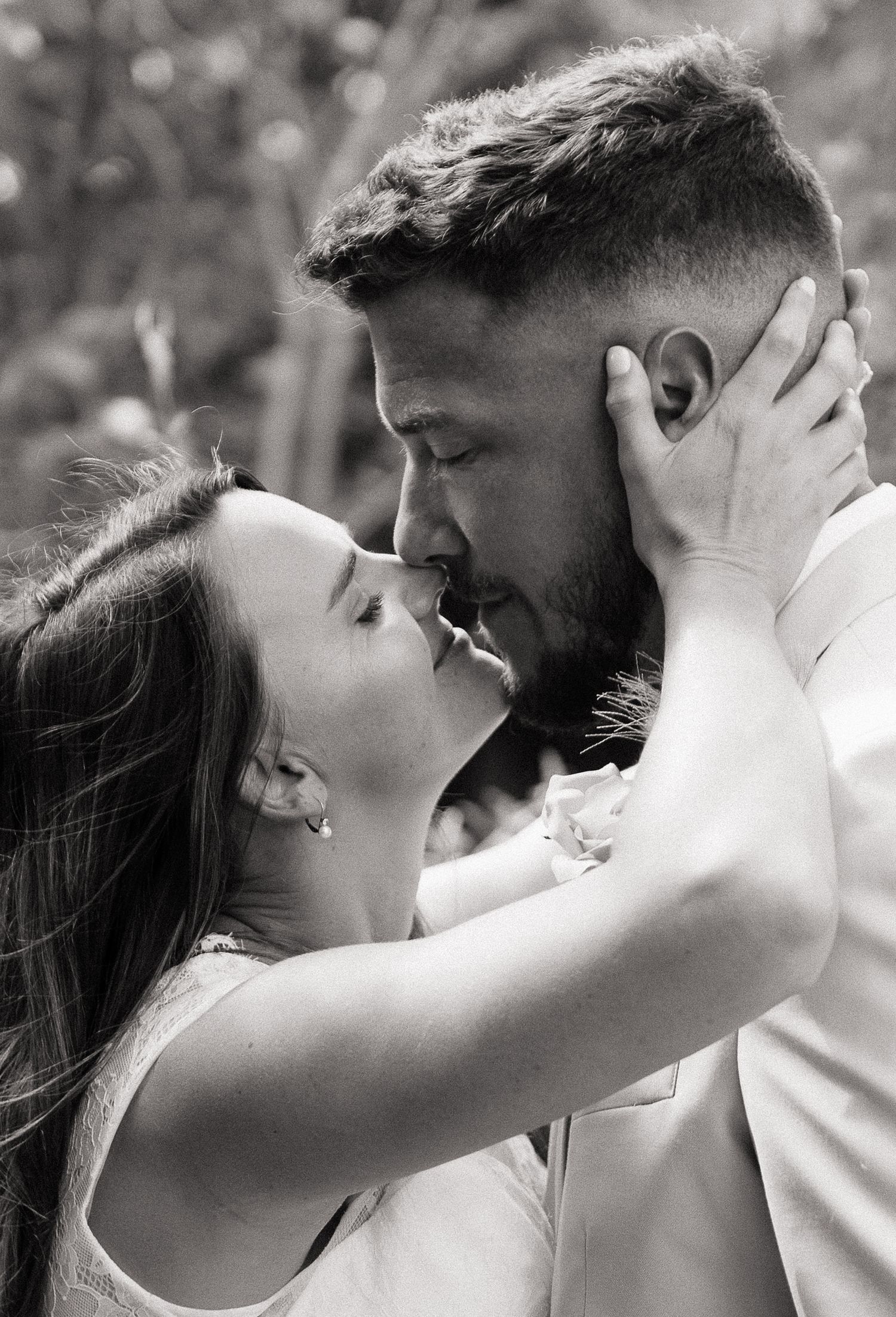 Black and white photo of a couple sharing a romantic kiss, the woman tenderly holding the man's face.
