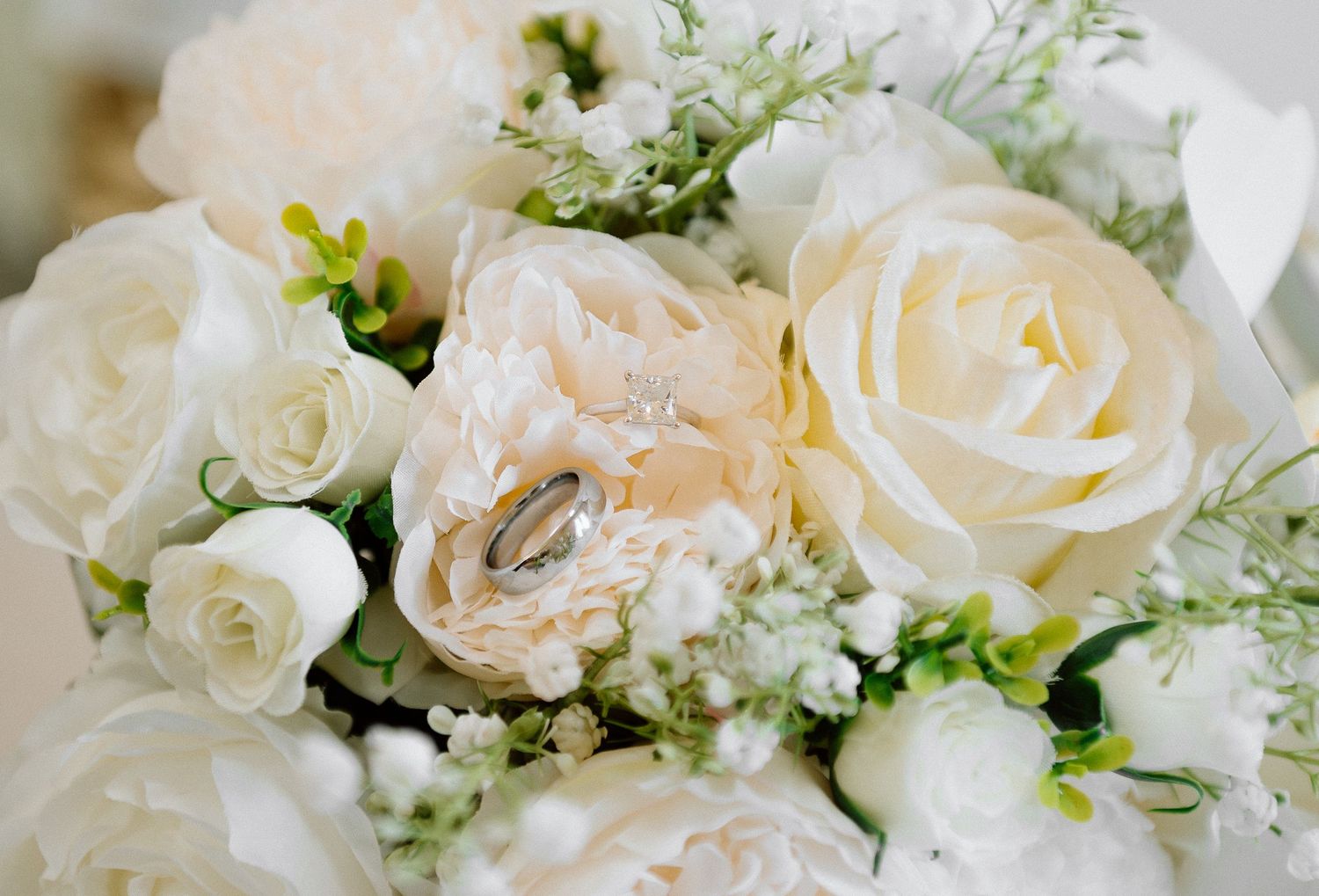 Delicate white and blush roses arranged with baby's breath and greenery in an elegant wedding bouquet.