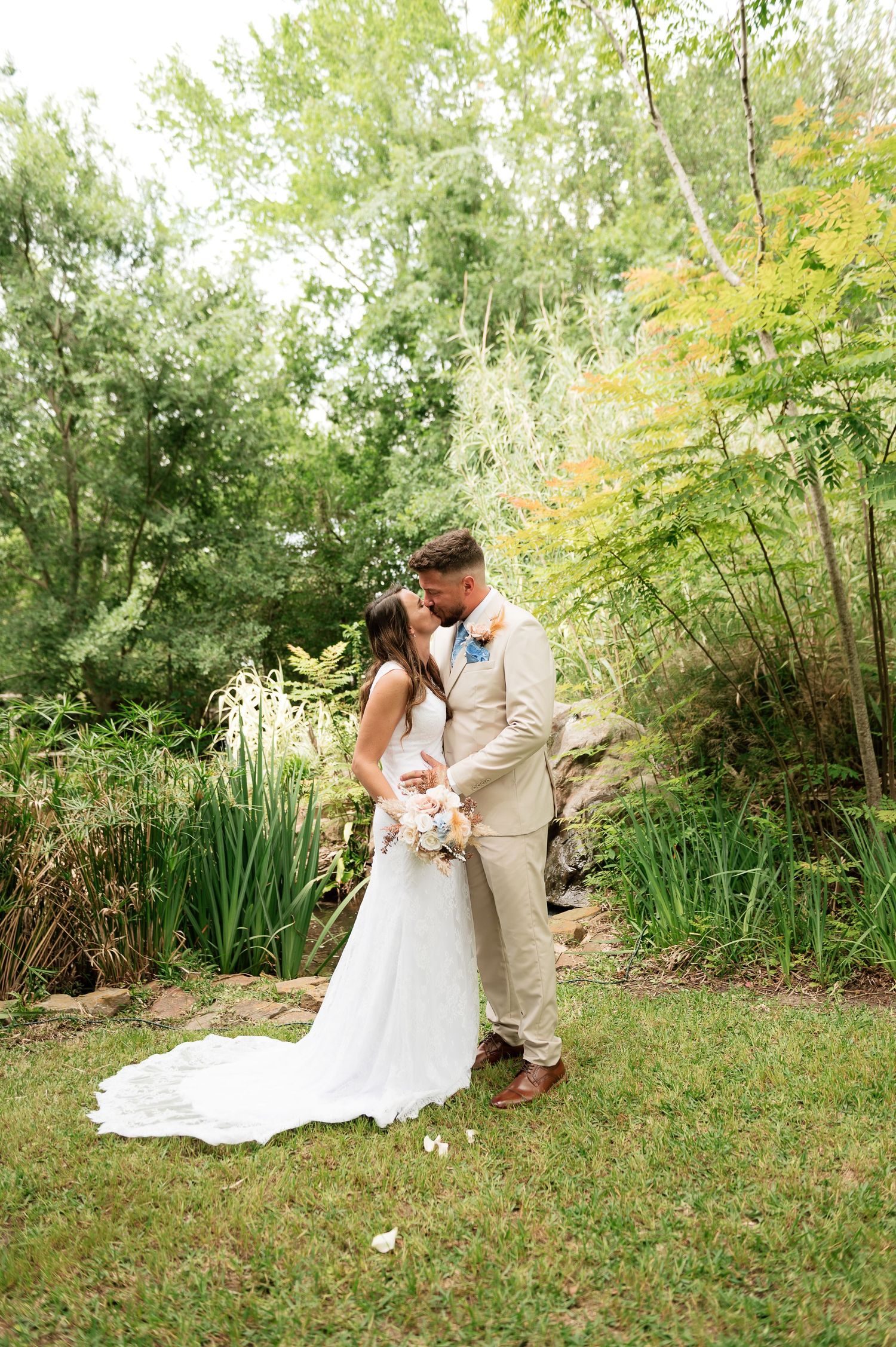 A bride and groom share a romantic moment in a lush garden, the bride in a white gown holding a bouquet.