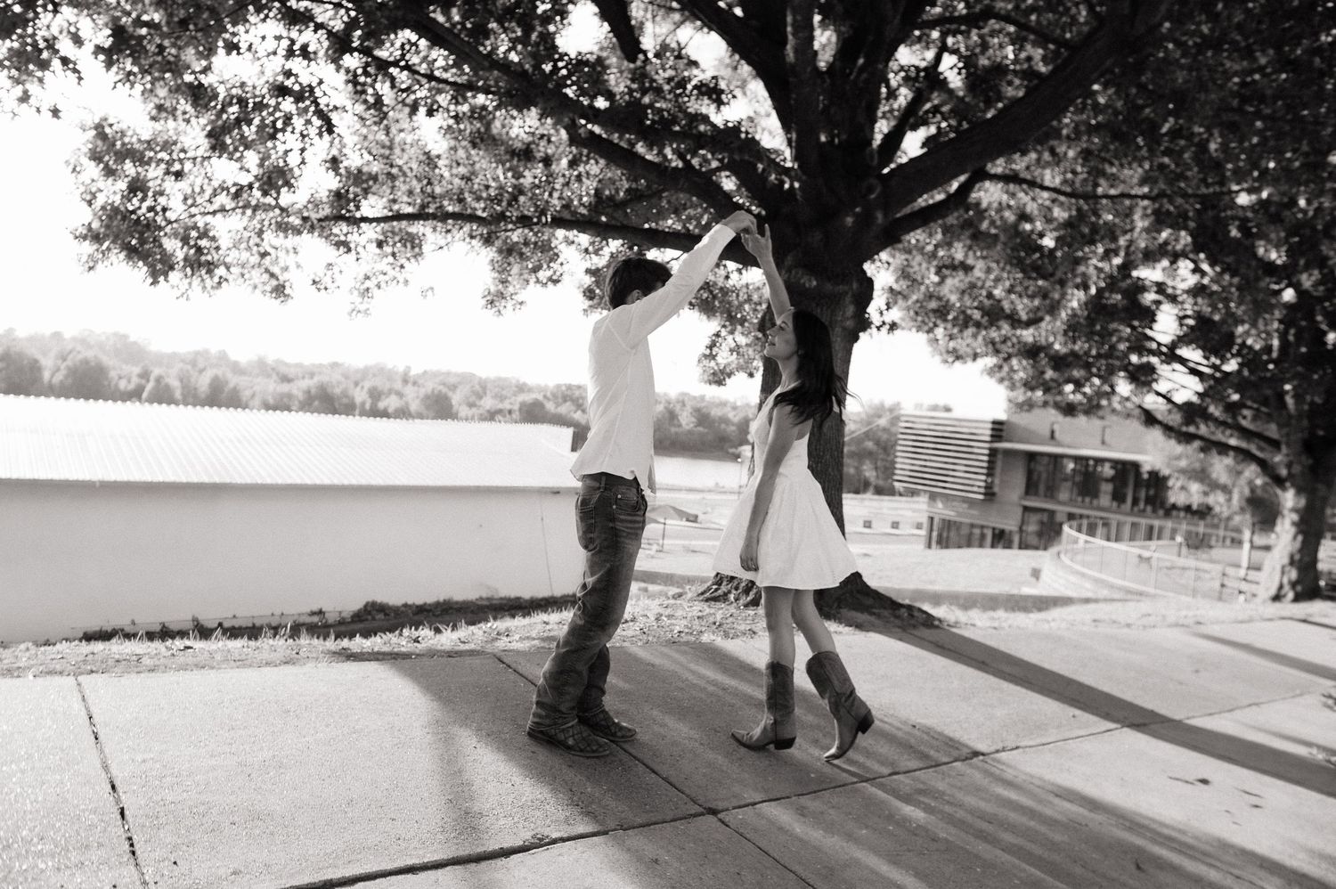 Black and white photo of a couple dancing outdoors near a tree on a wooden deck.