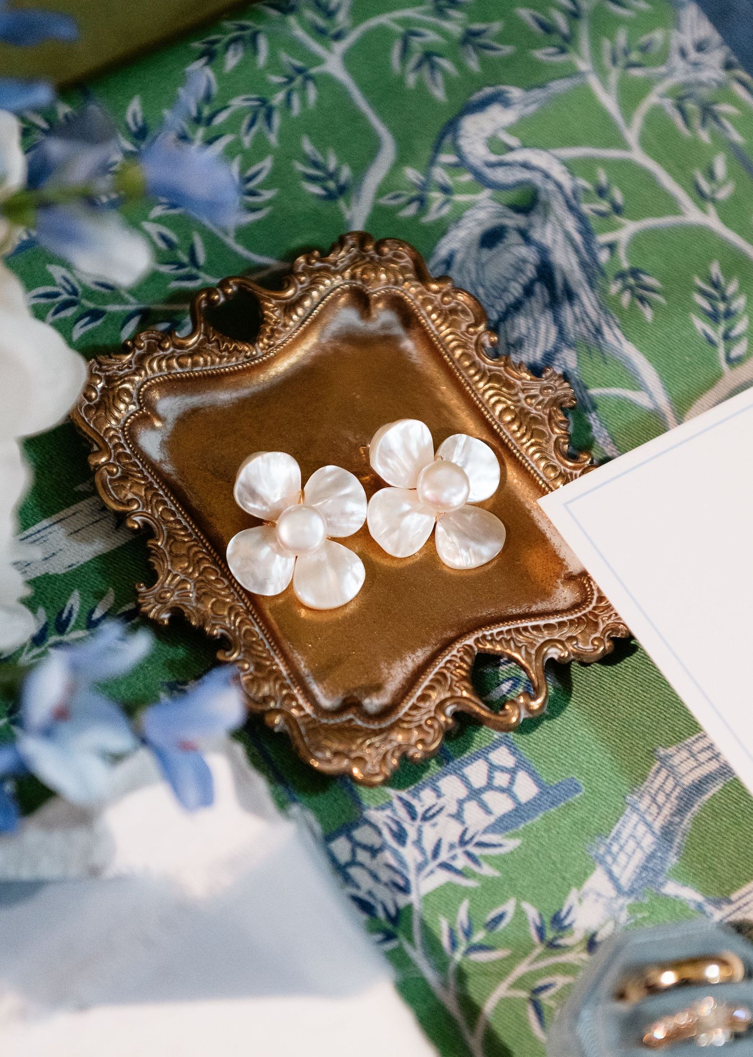 Pearl flower cluster earrings displayed on ornate gold tray atop green blue white chinoiserie floral fabric.