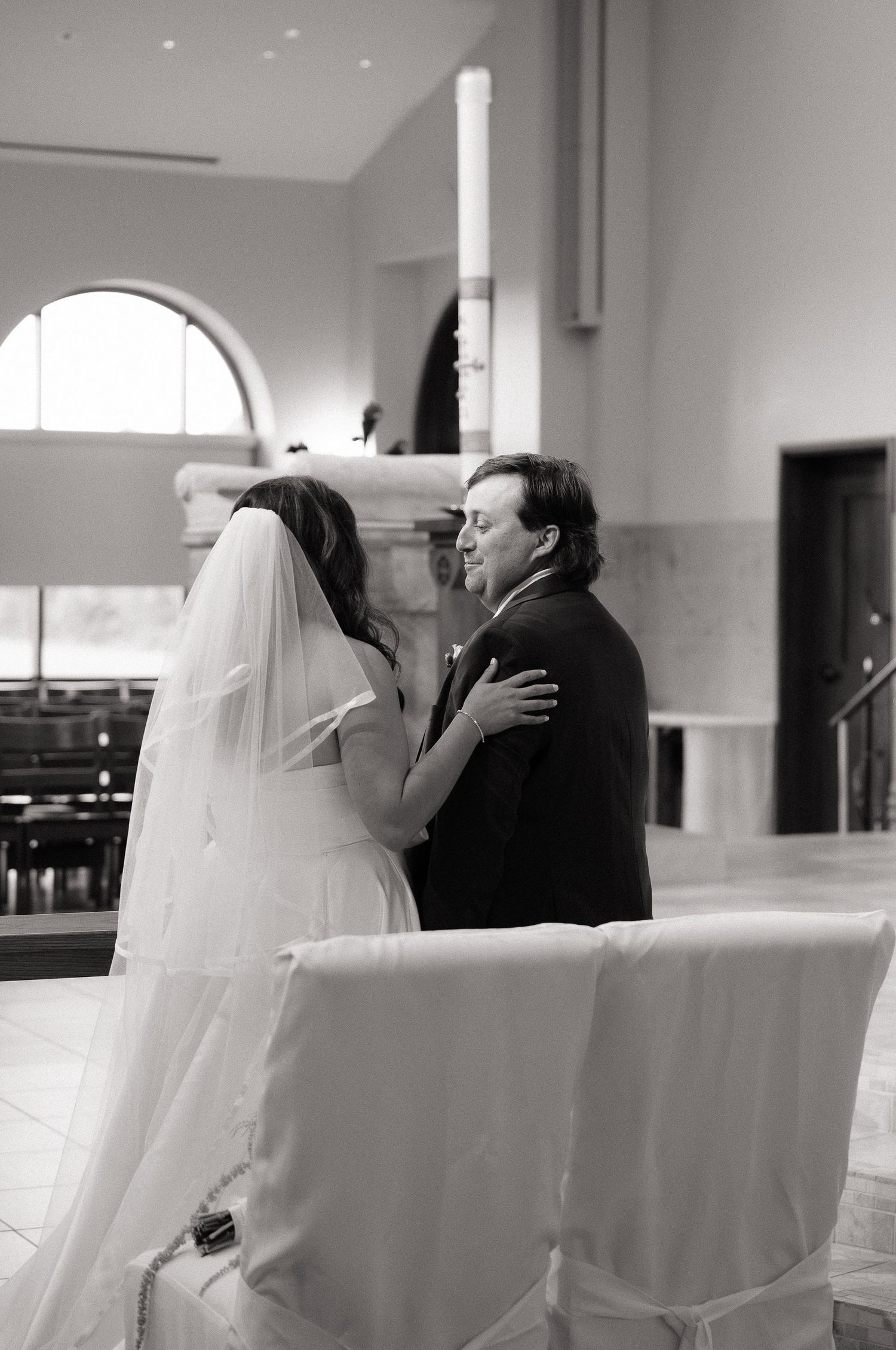 Black and white photo of a bride and groom sharing an intimate moment at the altar during their wedding ceremony.