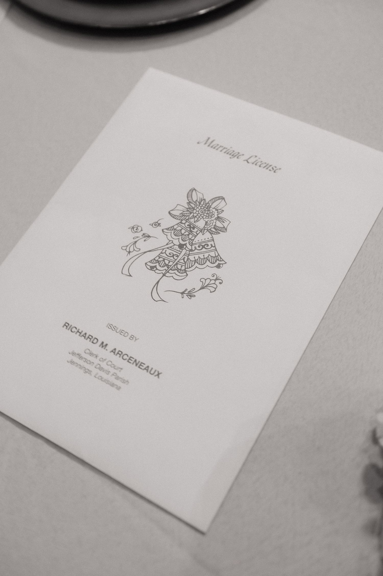 A marriage license document issued by Richard M. Arceneaux, featuring elegant wedding bell illustration on white paper.
